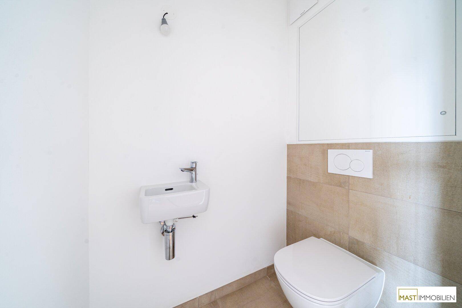 Modernes Gäste-WC mit wandhängender Toilette, kleinem Waschbecken und hellen Fliesen.