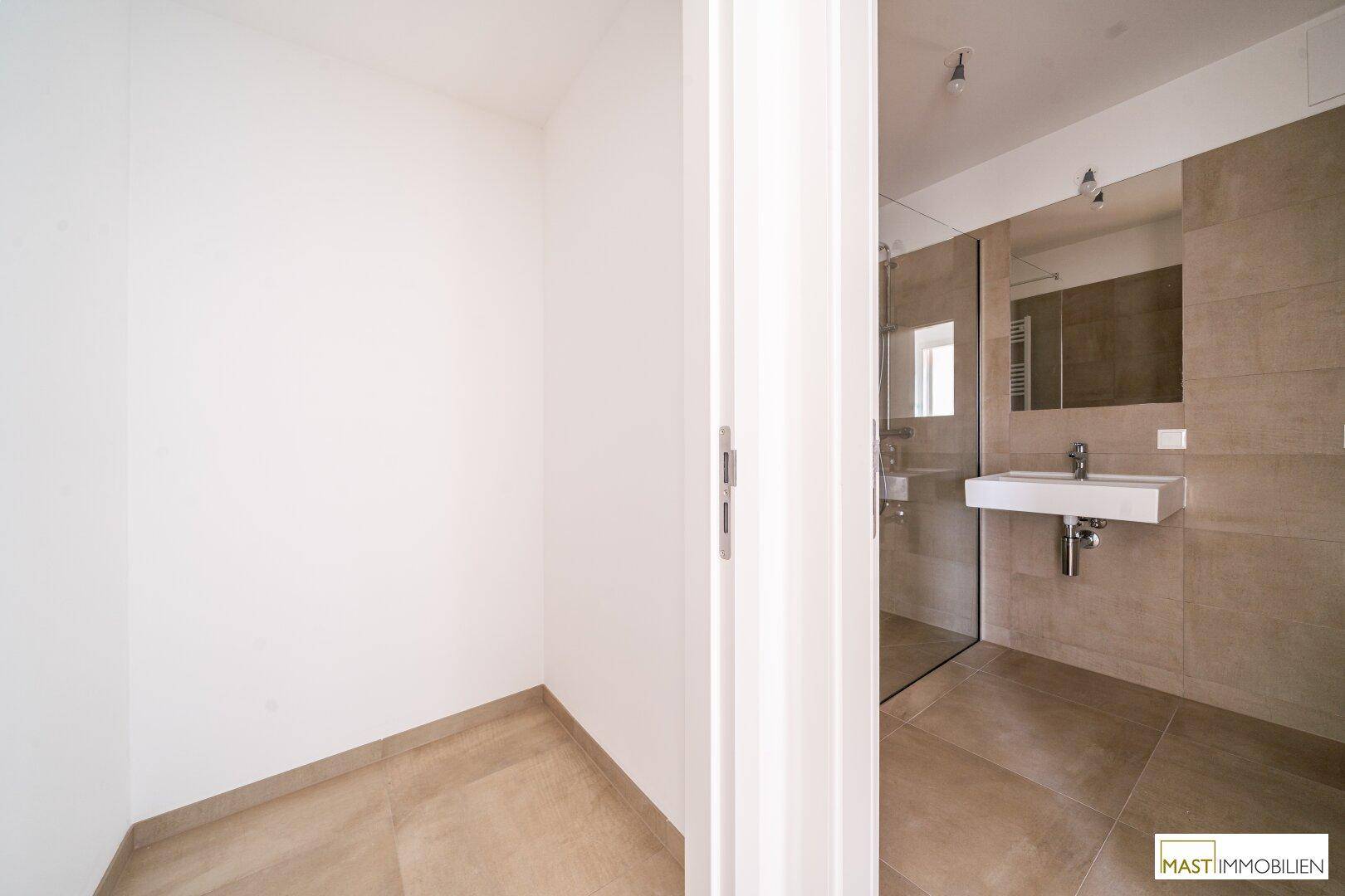 Eingangsbereich zu einem modernen Badezimmer mit Duschbereich und elegantem Waschbecken.