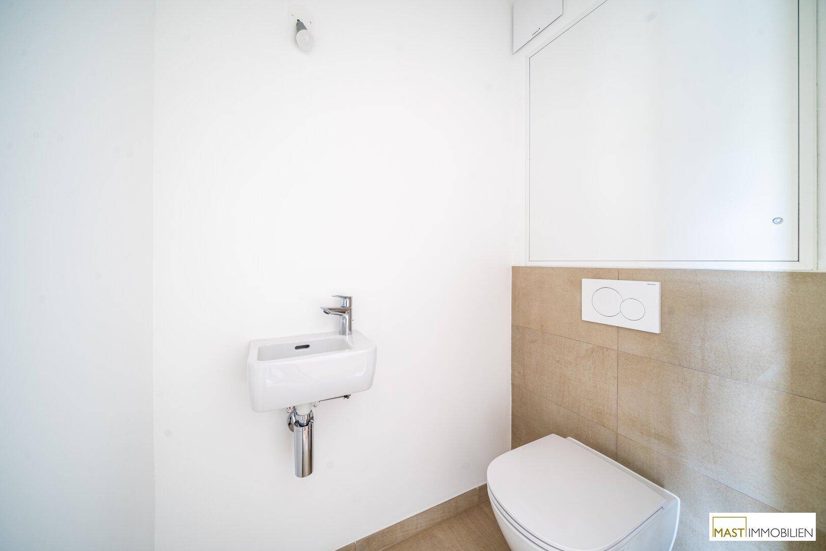 Modernes Gäste-WC mit Wand-WC, kleinem Waschbecken und beigefarbenen Fliesen.