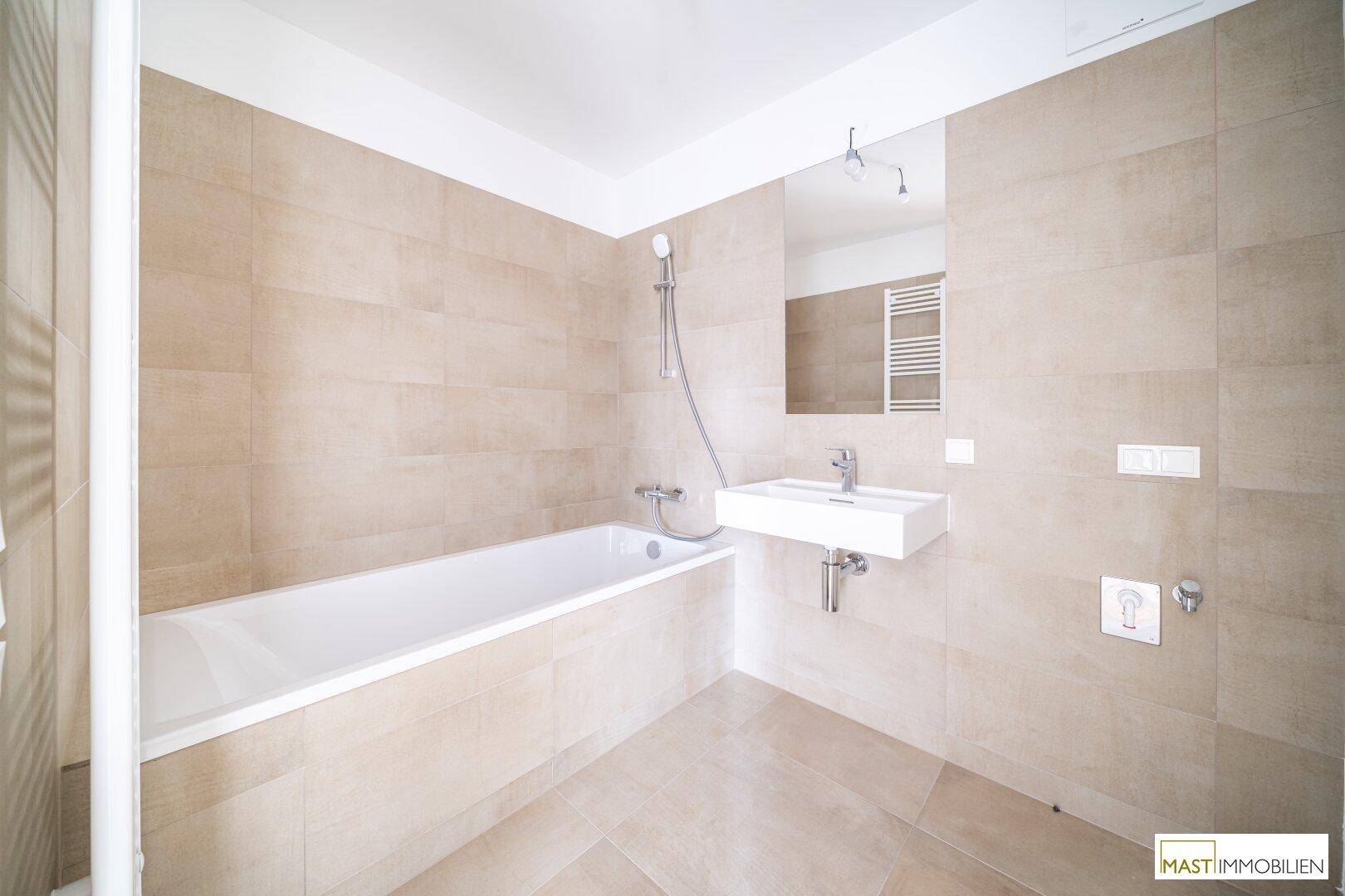 Zeitgemäßes Badezimmer mit Badewanne, integrierter Dusche, modernem Waschbecken und beheiztem Handtuchhalter.