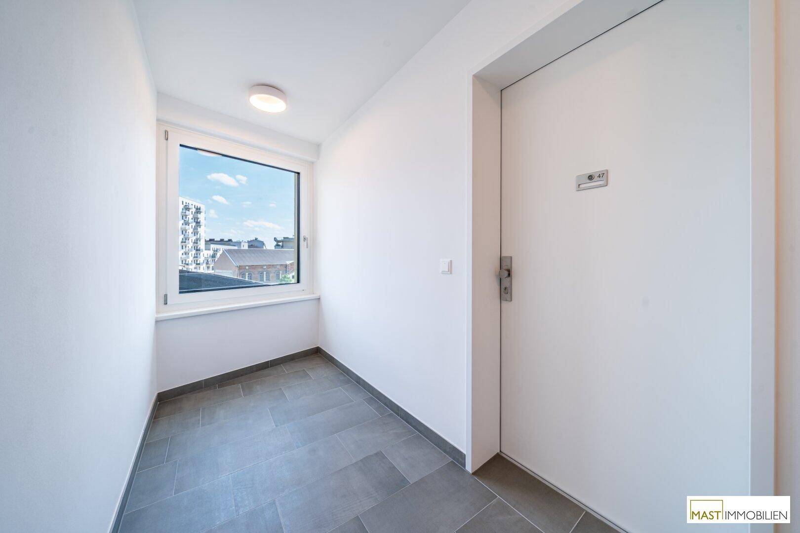 Heller Flur mit Fliesenboden und Fenster, bietet einen Blick nach draußen.