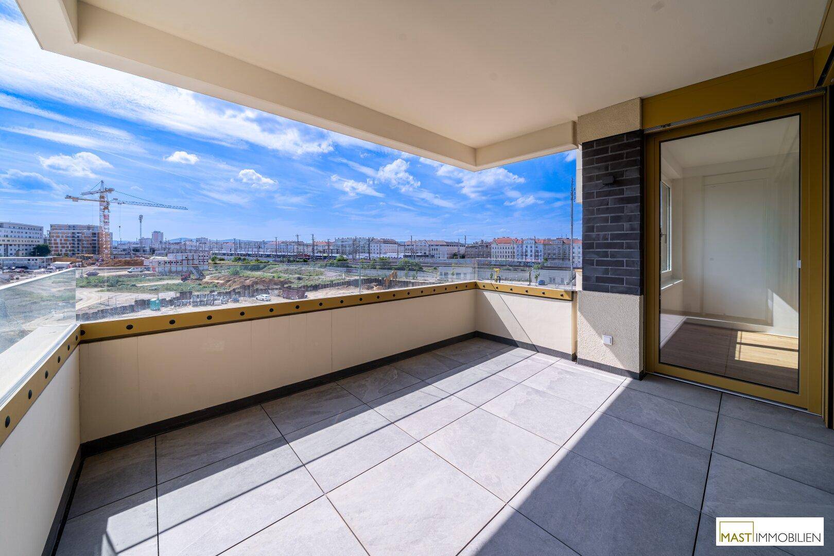 Geräumiger Balkon mit Fliesenboden und Glasgeländer, bietet einen weiten Blick über die Stadt.