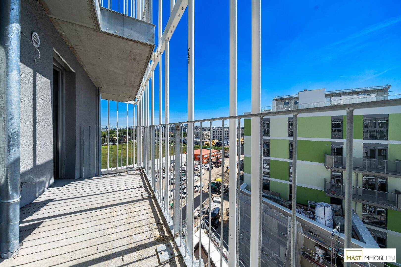 Balkon eines Neubaus mit weitem Blick über die städtische Umgebung und weitere Bauprojekte.