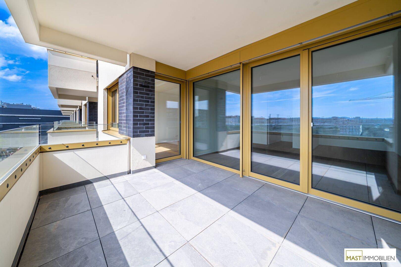 Heller Balkon mit großen Schiebetüren und Fliesenboden, ideal für entspannte Stunden im Freien.