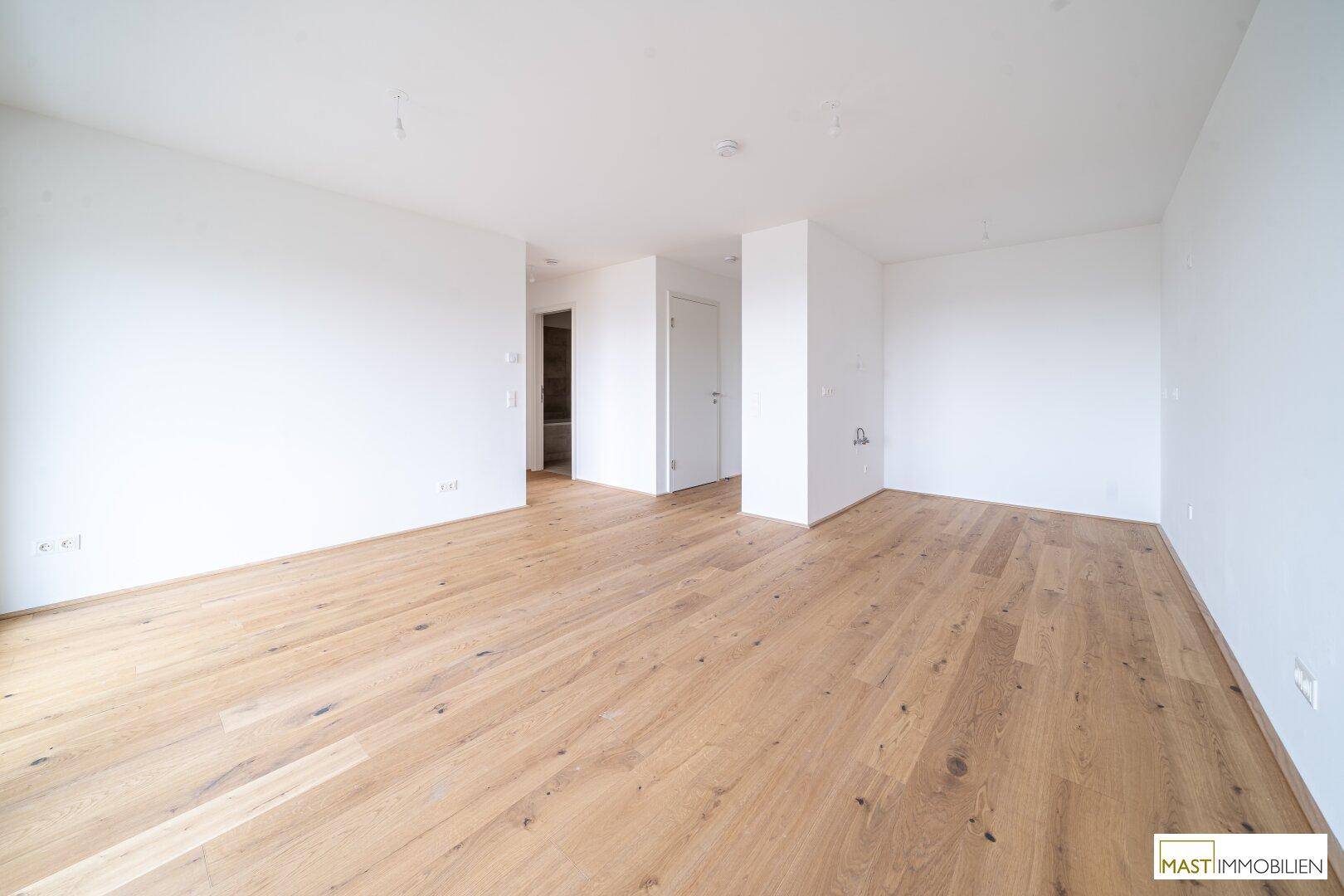 Geräumiges, helles Zimmer mit Holzboden und weiß gestrichenen Wänden, bereit zur individuellen Gestaltung.