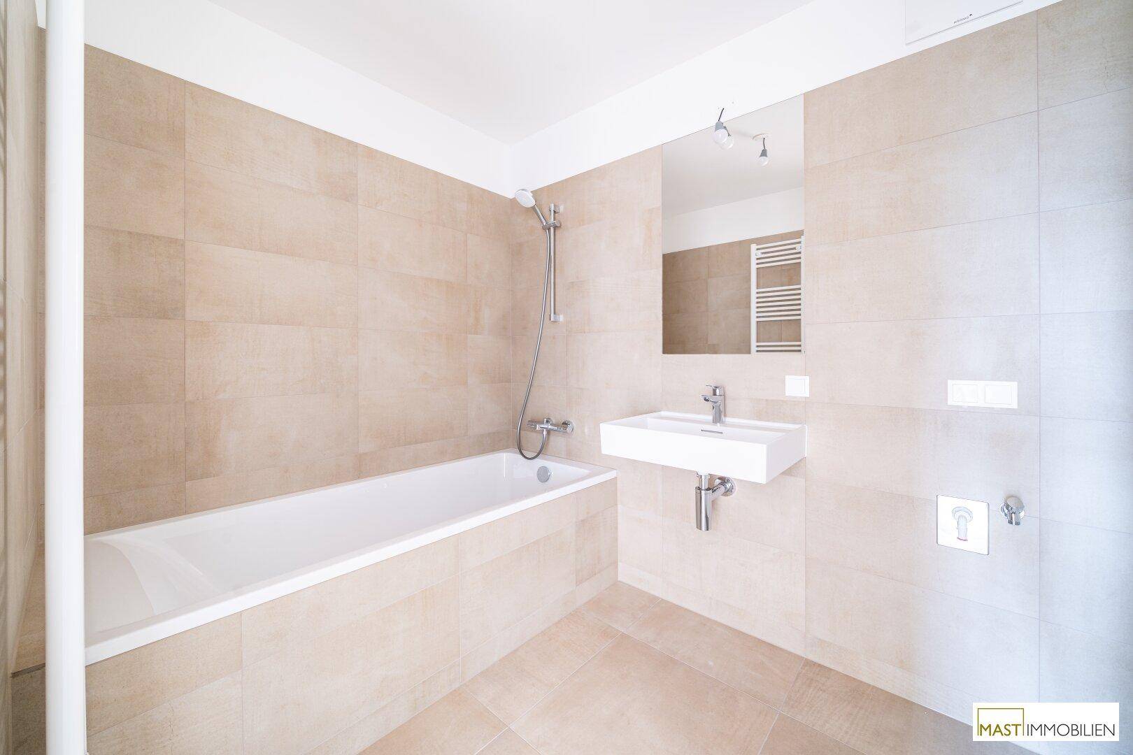 Helles Badezimmer mit Badewanne, modernem Waschbecken und beheiztem Handtuchhalter.