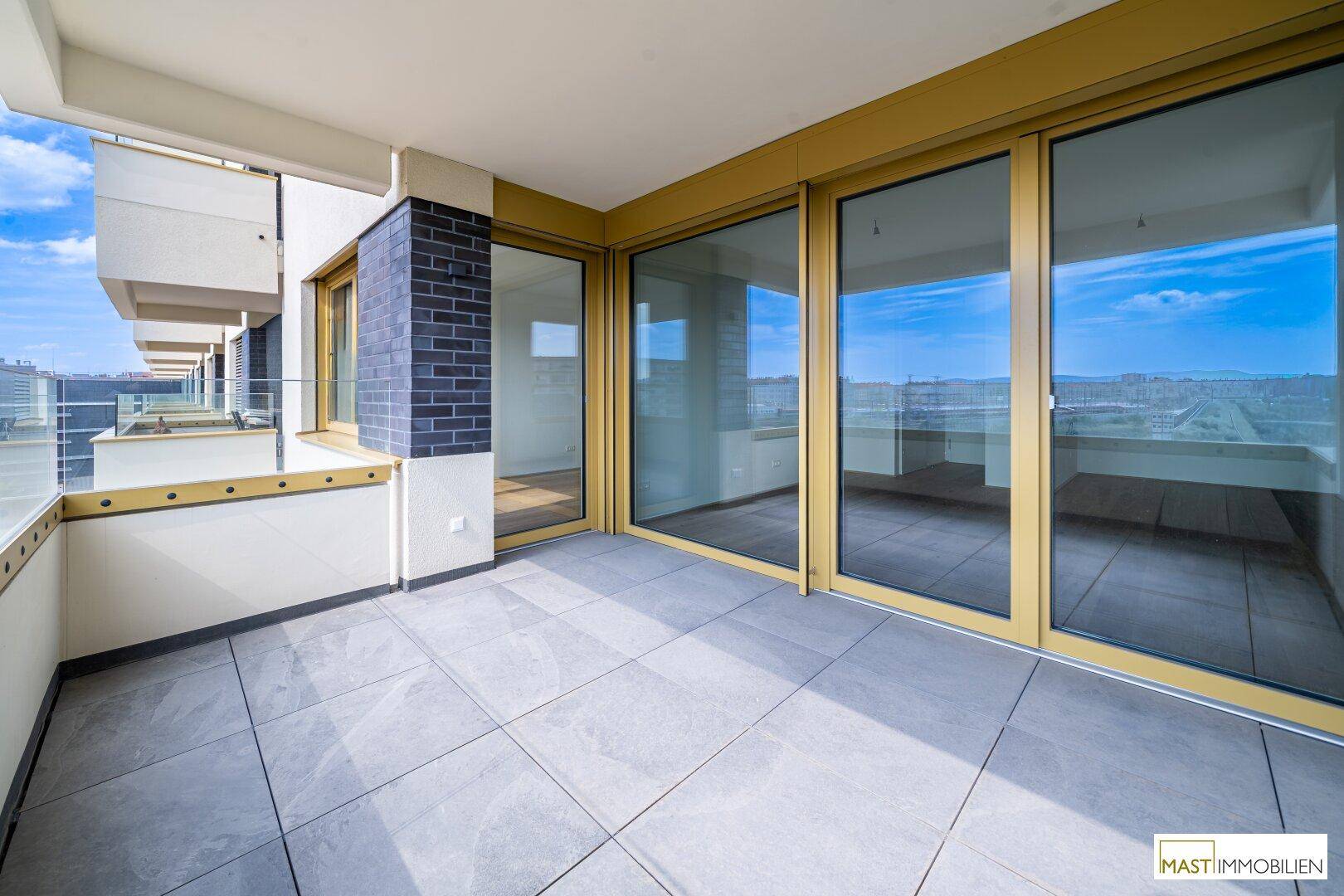 Heller Balkon mit Fliesenboden und Zugang zu den Innenräumen, mit Panoramablick über die Stadt.