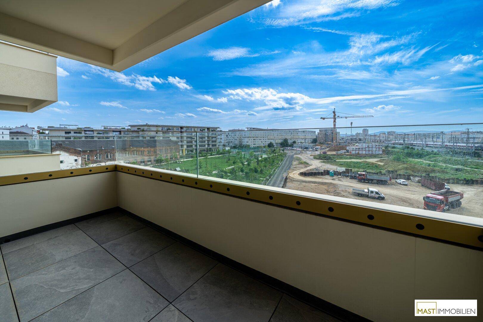 Großer Balkon mit Fliesenboden und freiem Blick auf die Stadt und den Himmel.