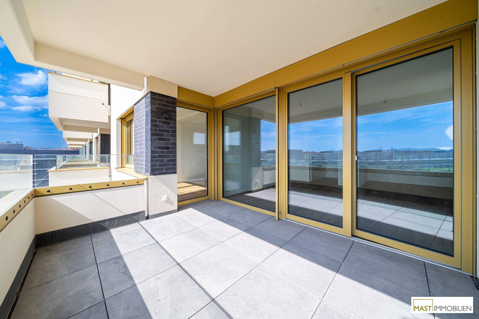 Heller Balkon mit Fliesenboden und raumhohen Fenstern, die den Zugang zum Innenraum ermöglichen.