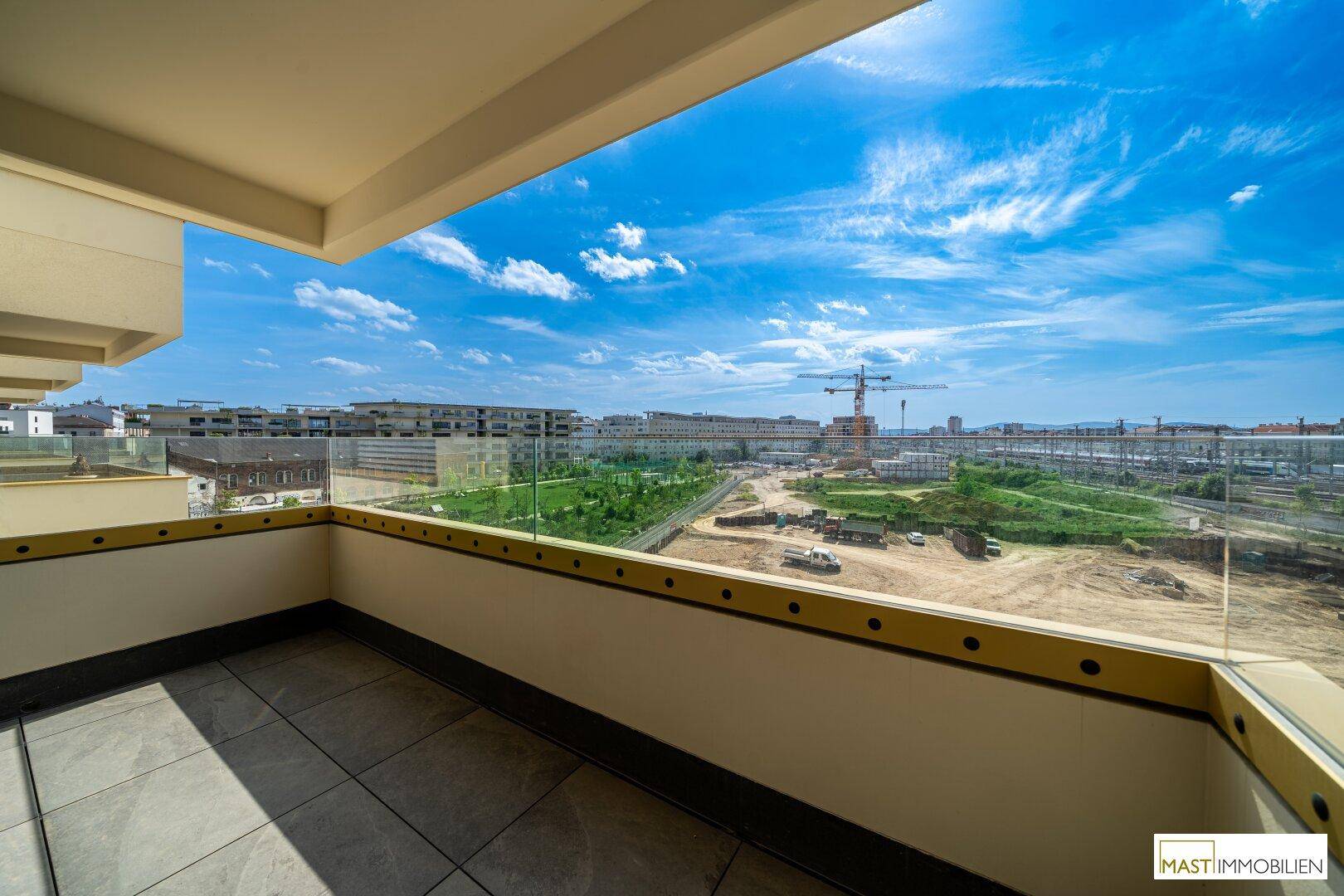Geräumiger Balkon mit Fliesenboden und Glasbrüstung bietet einen weiten Blick auf die Stadt.