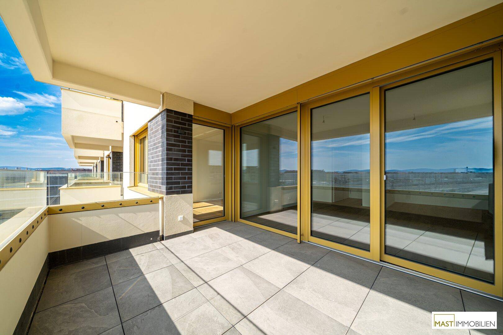 Große geflieste Terrasse mit Schiebetüren und weitem Blick über die städtische Umgebung.