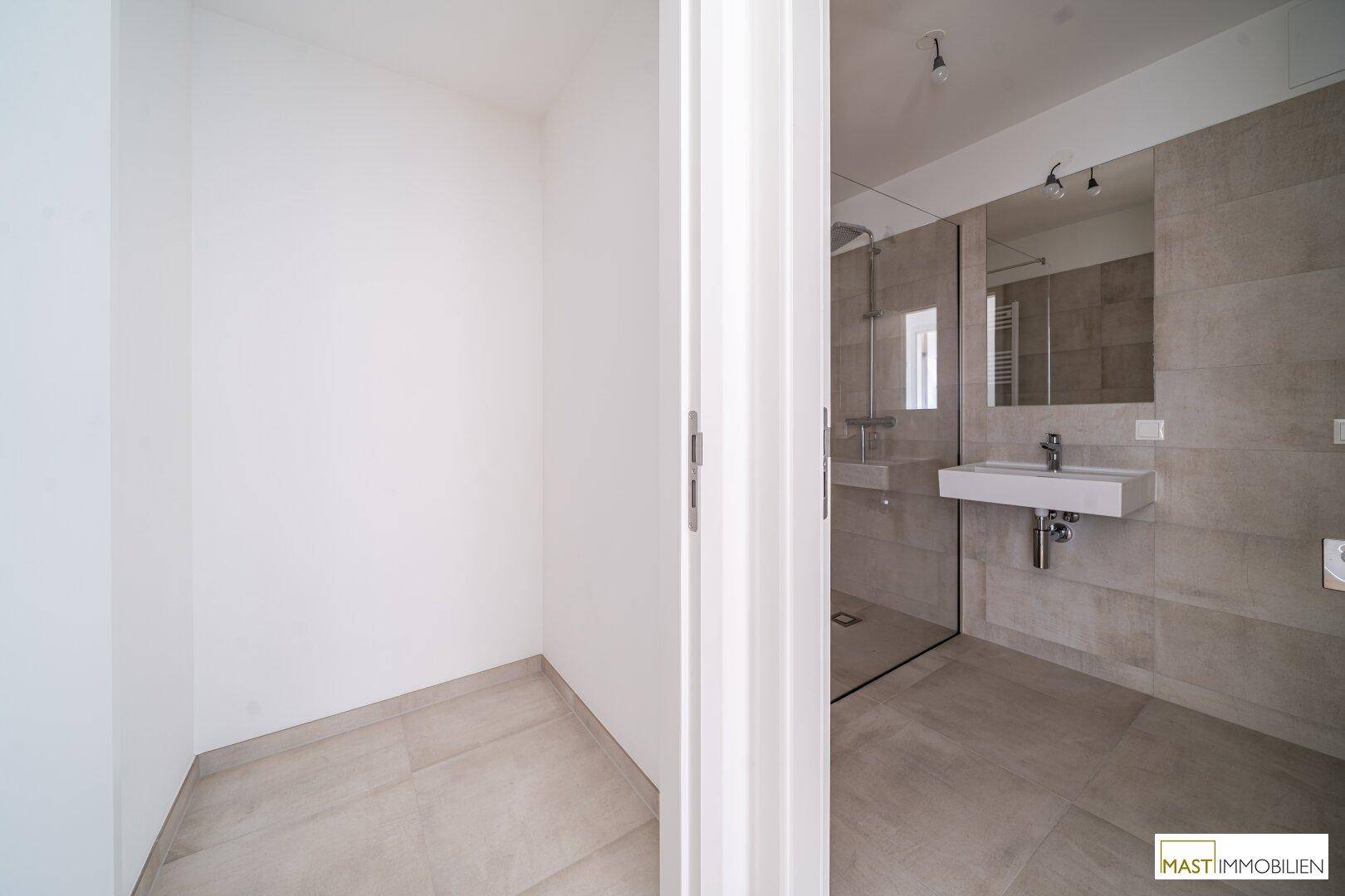 Modernes Badezimmer mit Fliesenboden, Waschbecken und einer geräumigen begehbaren Dusche.