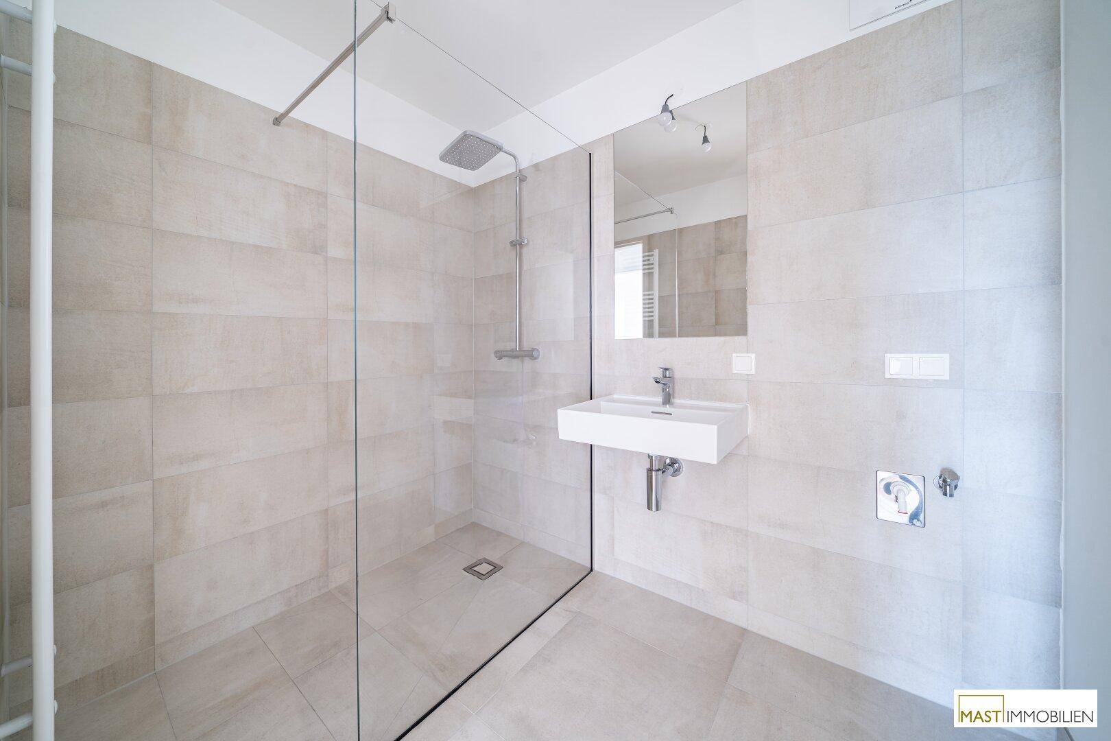 Detailansicht des modernen Badezimmers mit großer begehbarer Dusche und elegantem Waschbecken.