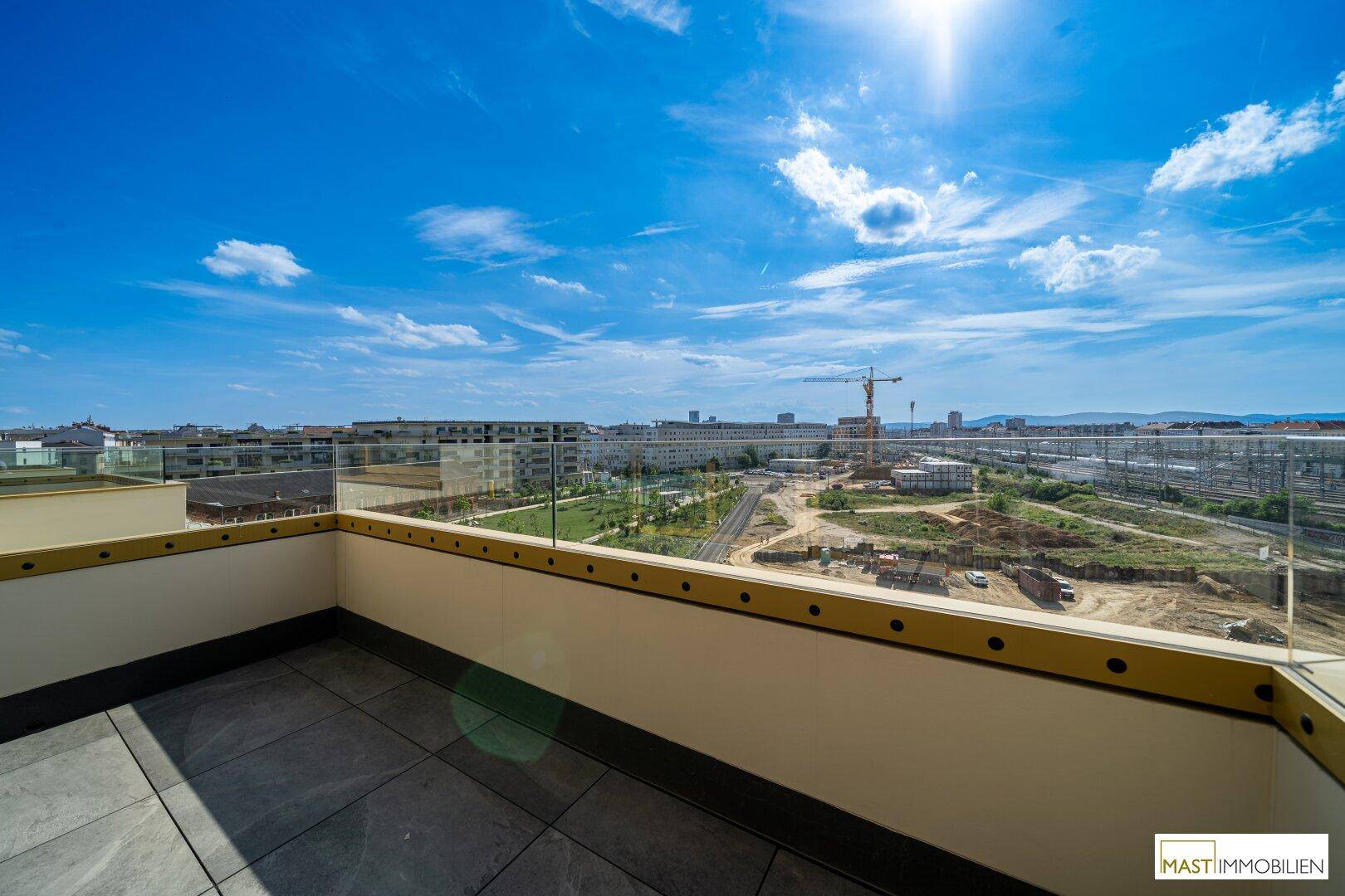Sonniger Balkon mit Fliesenboden und Glasgeländer bietet einen weiten Panoramablick über die Stadt.