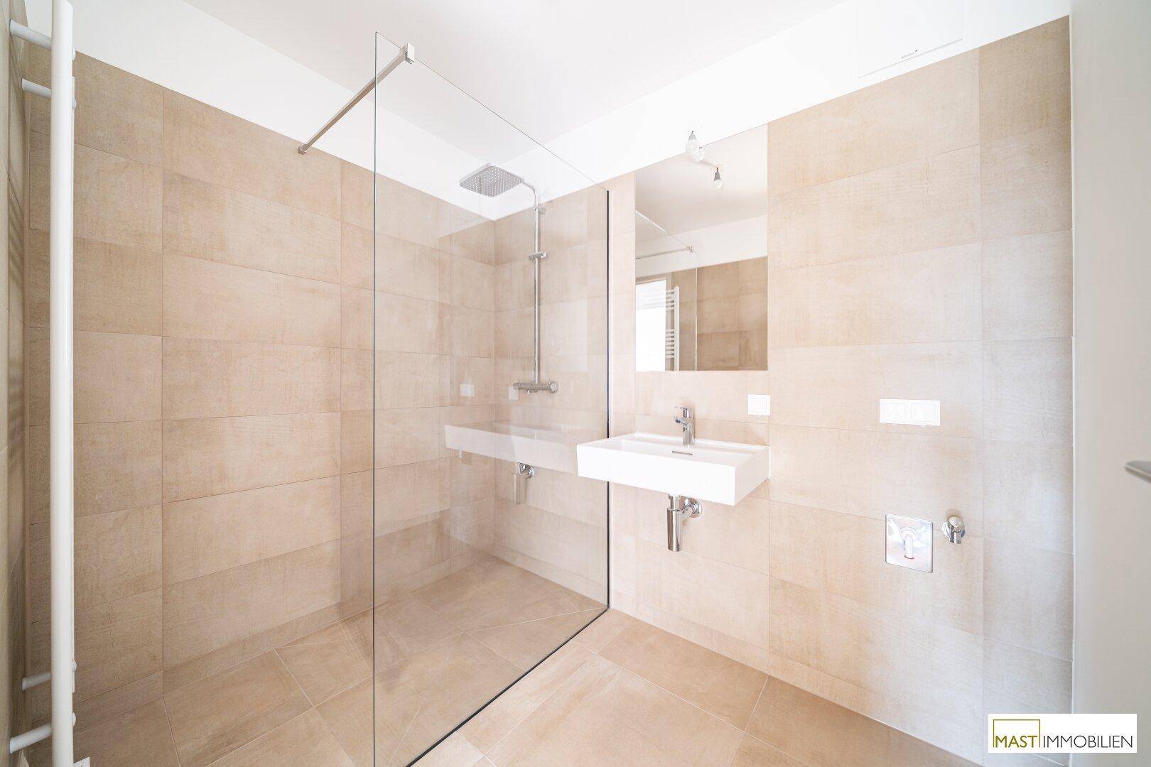 Modernes Badezimmer mit großer begehbarer Dusche, eleganten Fliesen und minimalistischem Design.