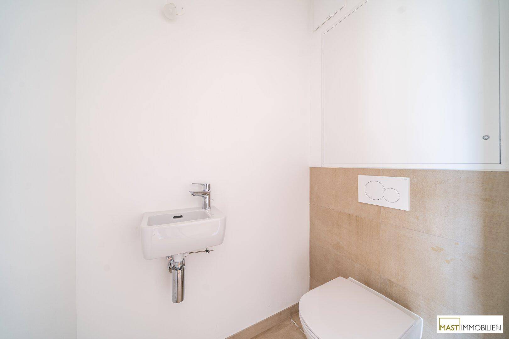 Separates Gäste-WC mit wandhängender Toilette und kleinem Waschbecken.