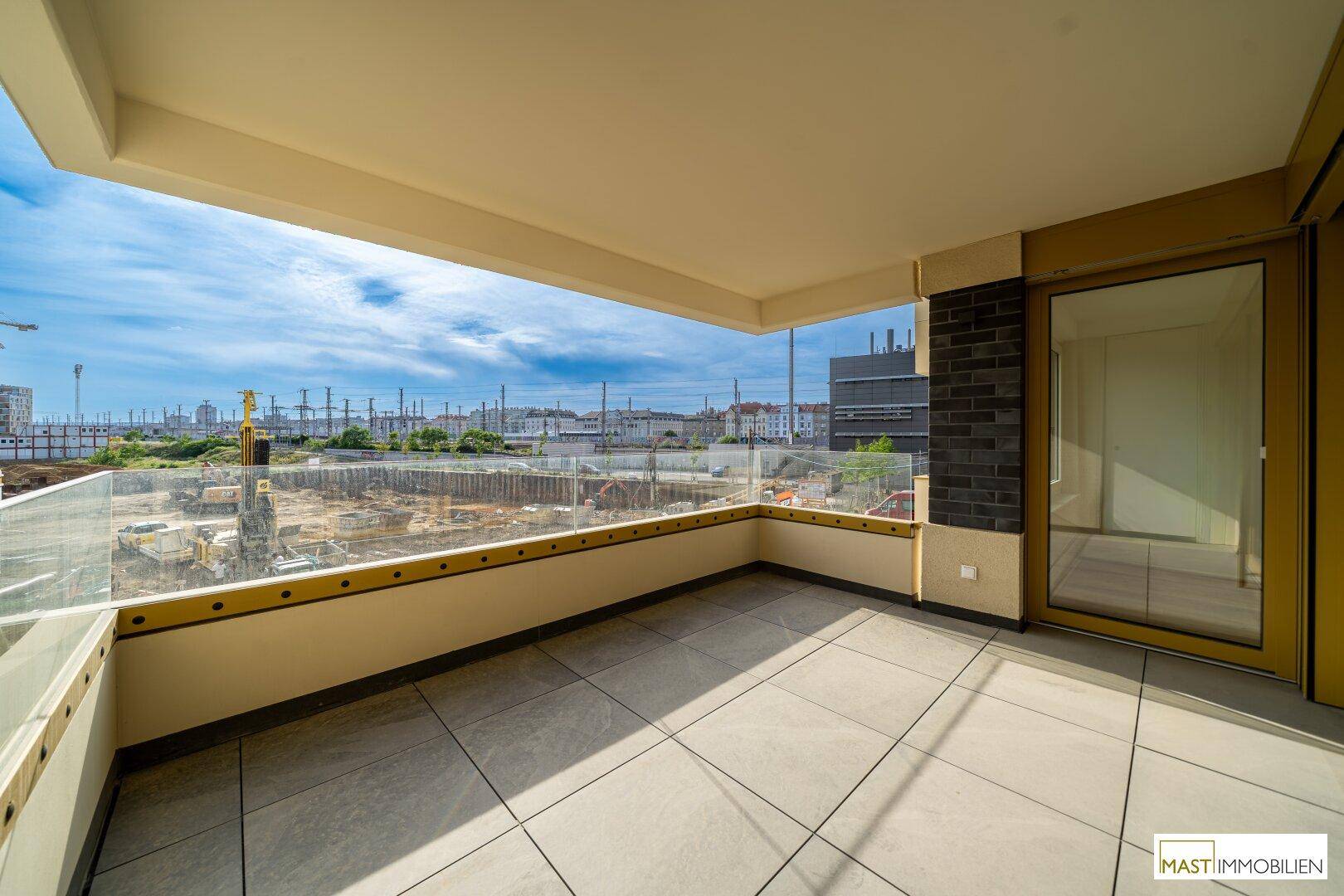 Geräumiger Balkon mit Fliesenboden und Glasbrüstung, bietet einen weiten Blick auf die Umgebung.