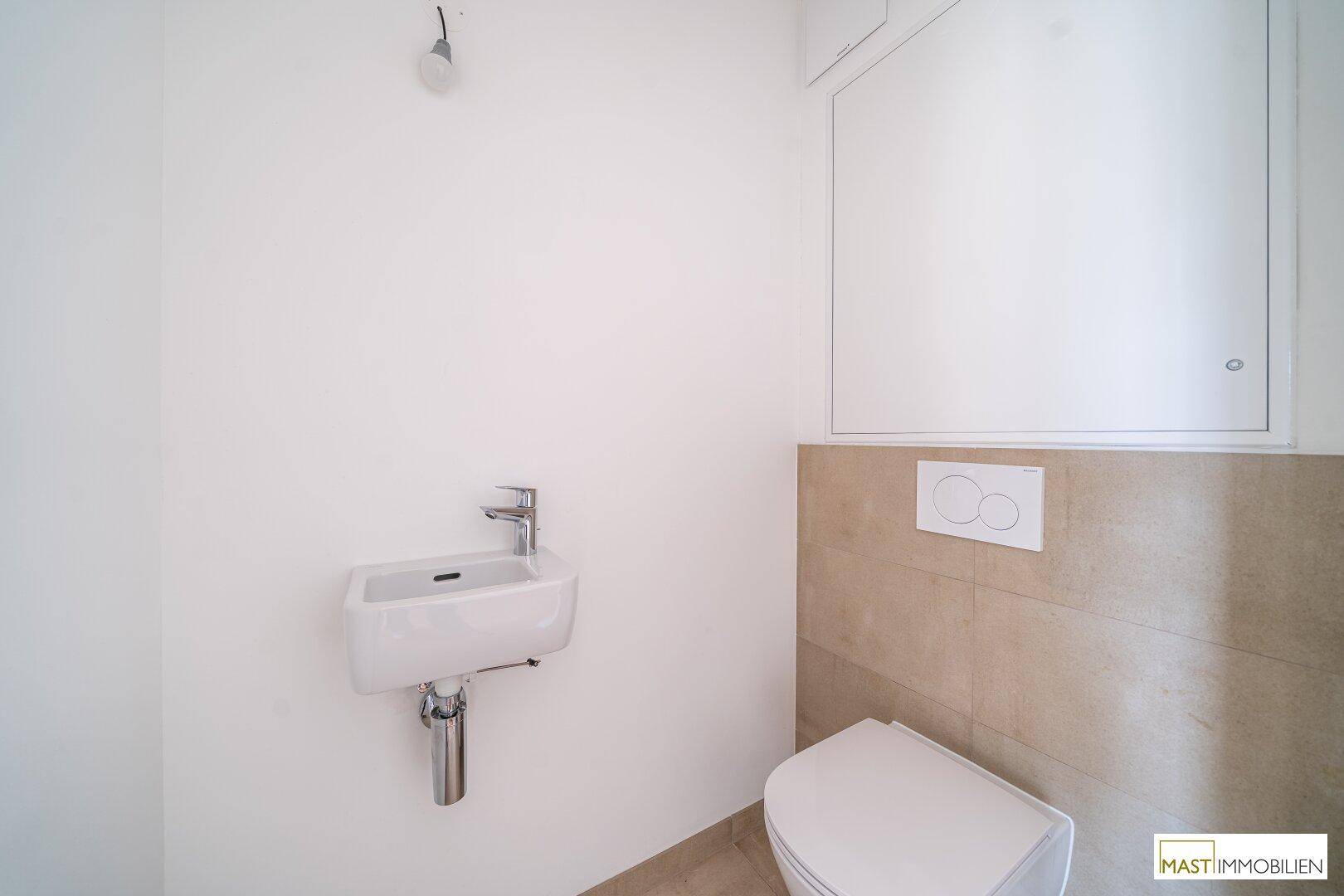Kleines Gäste-WC mit wandhängender Toilette und kompaktem Waschbecken, halbhoch gefliest.