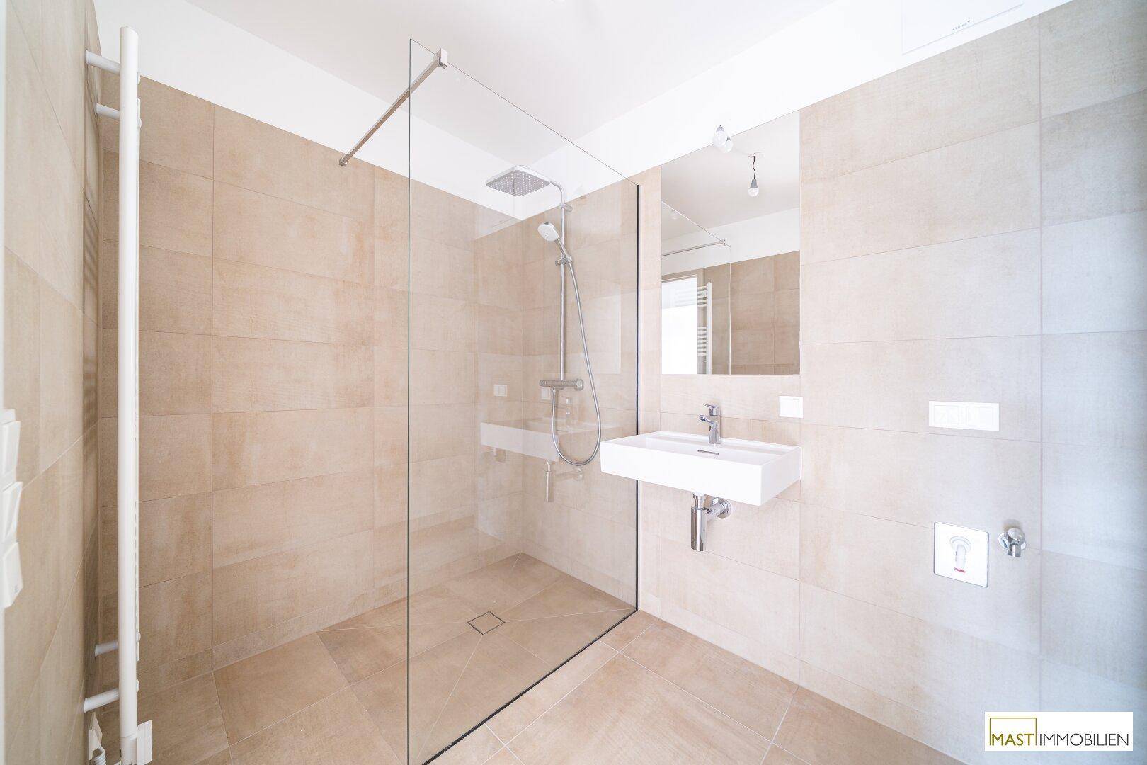 Modernes Badezimmer mit begehbarer Dusche, Einzelwaschbecken und beigefarbenen Fliesen.