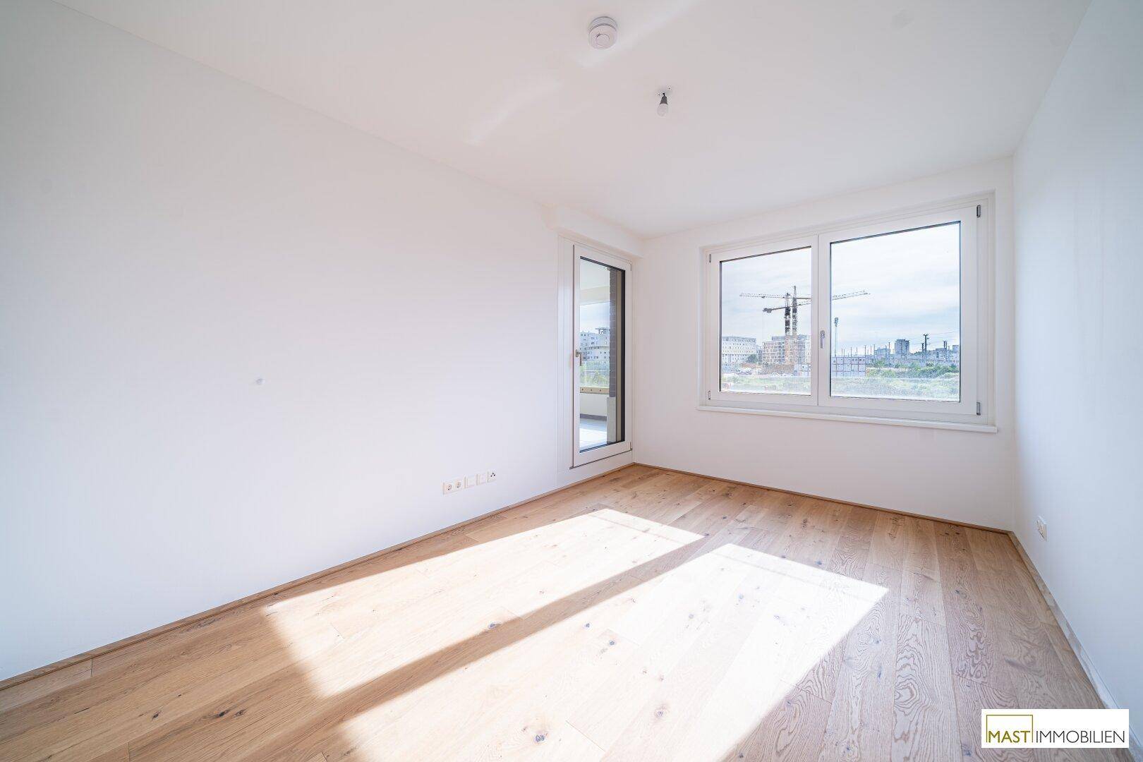 Helles Schlafzimmer mit Parkettboden und Zugang zu einem Außenbereich, ideal für Ruhe und Entspannung.