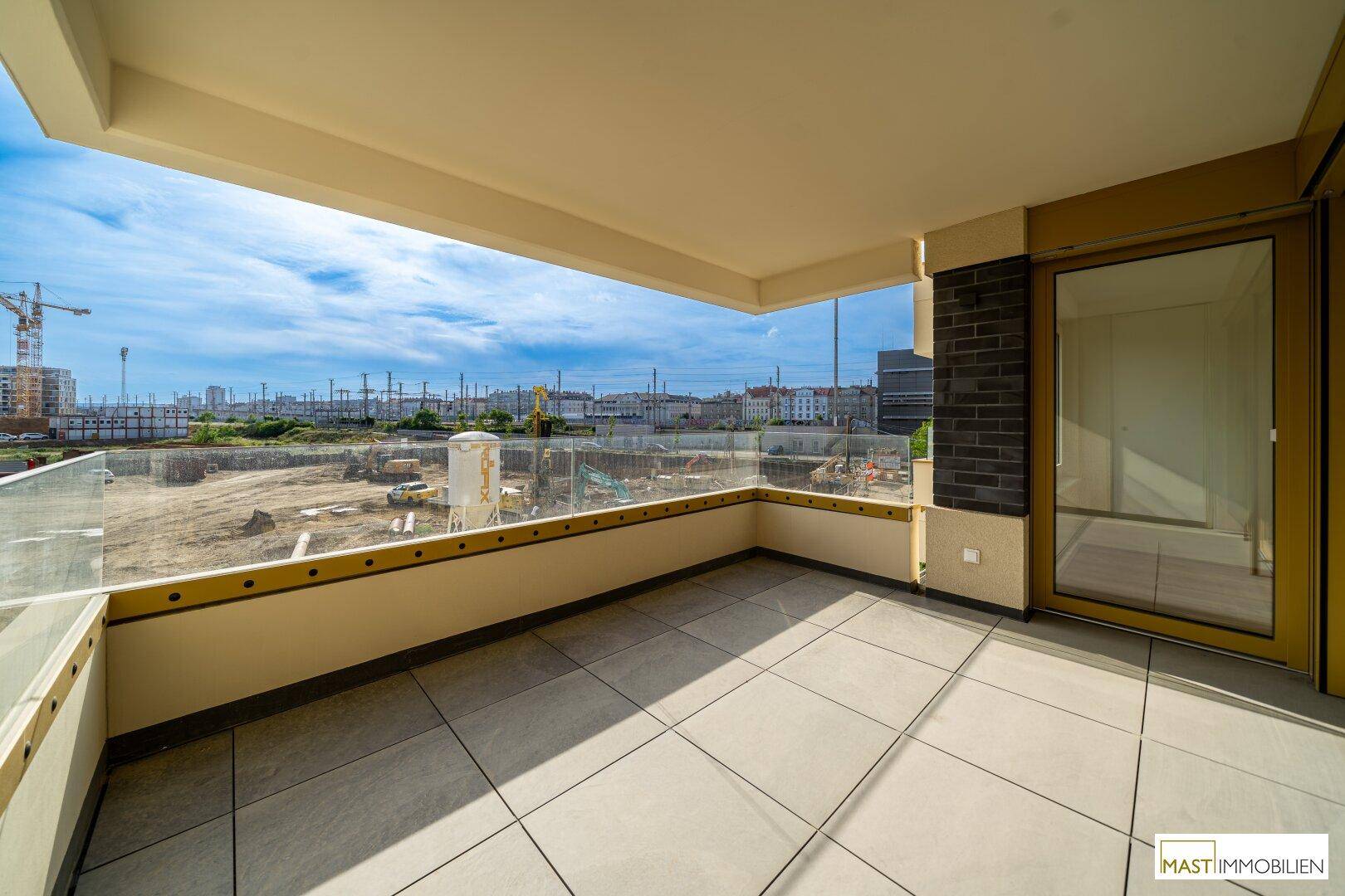 Geräumiger Balkon mit modernen Fliesen und Glasgeländer, bietet Zugang zum Innenbereich und weite Aussicht.