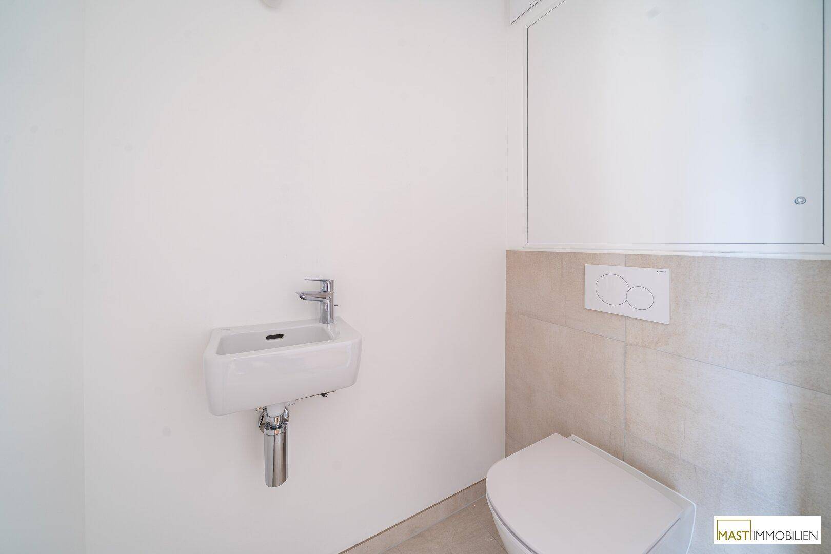 Separates Gäste-WC mit kleinem Waschbecken und Wand-WC, in modernem Design gehalten.