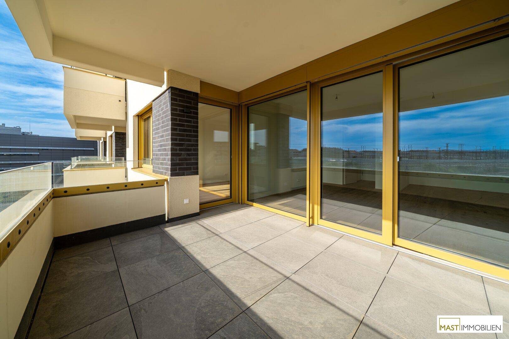 Breiter Balkon mit Fliesenboden und Blick auf die Umgebung, ideal für entspannte Stunden im Freien.