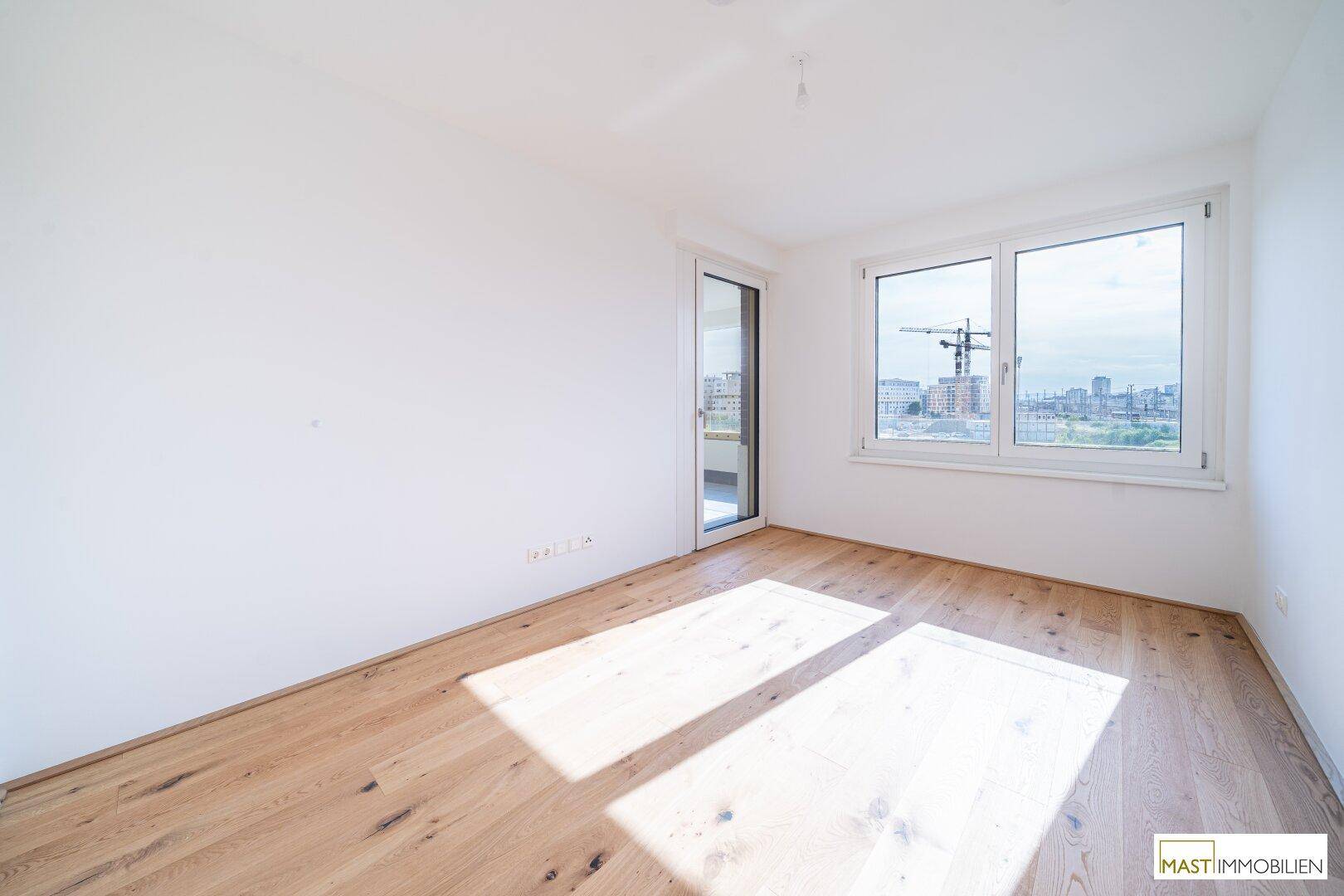 Lichtdurchflutetes Schlafzimmer mit Holzboden und großem Fenster, bietet viel Tageslicht.