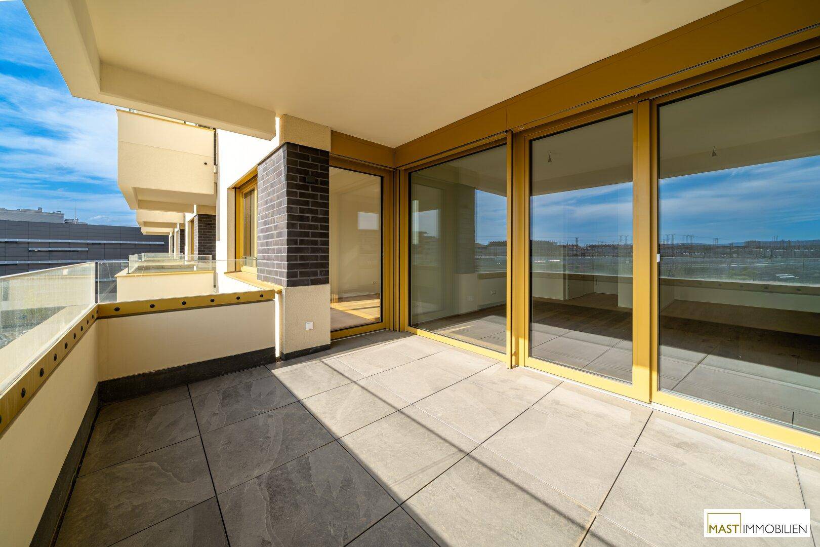 Heller Balkon mit modernen Fliesen und großen Schiebetüren, ideal für Entspannung im Freien.