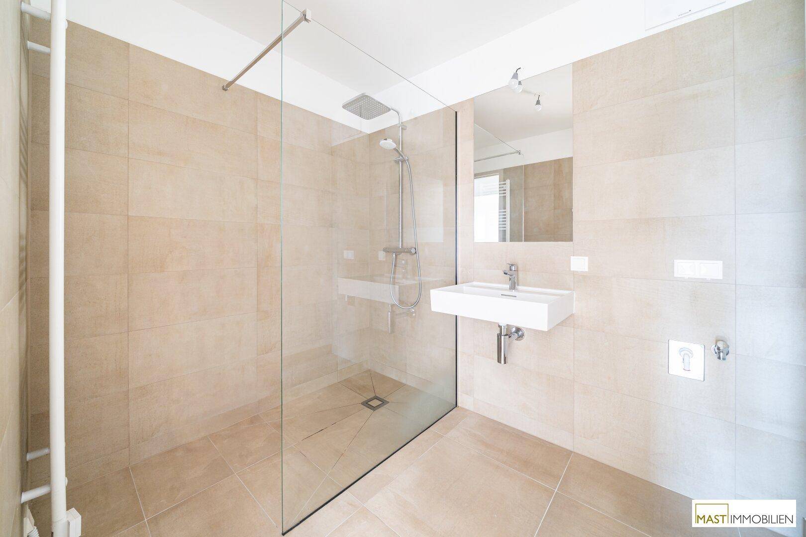 Modernes Badezimmer mit ebenerdiger Dusche, Einzelwaschbecken und beigefarbenen Fliesen.