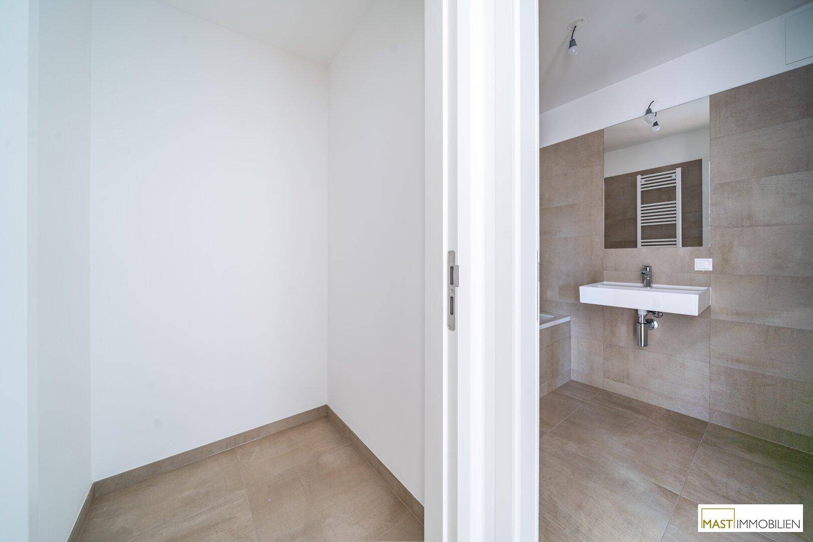 Modernes Badezimmer mit beigefarbenen Fliesen, Einzelwaschbecken und beheiztem Handtuchhalter.