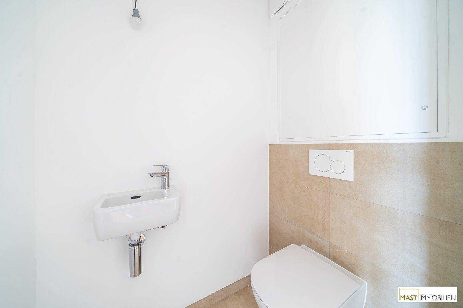 Kleines Gäste-WC mit Wand-WC, modernem Waschbecken und beigen Fliesen.