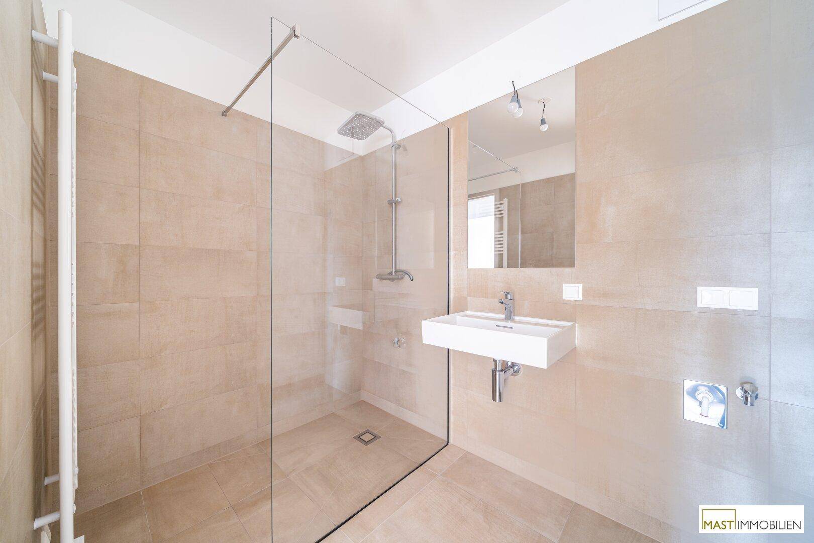 Helles Badezimmer mit begehbarer Dusche, modernem Waschbecken und beigen Fliesen.