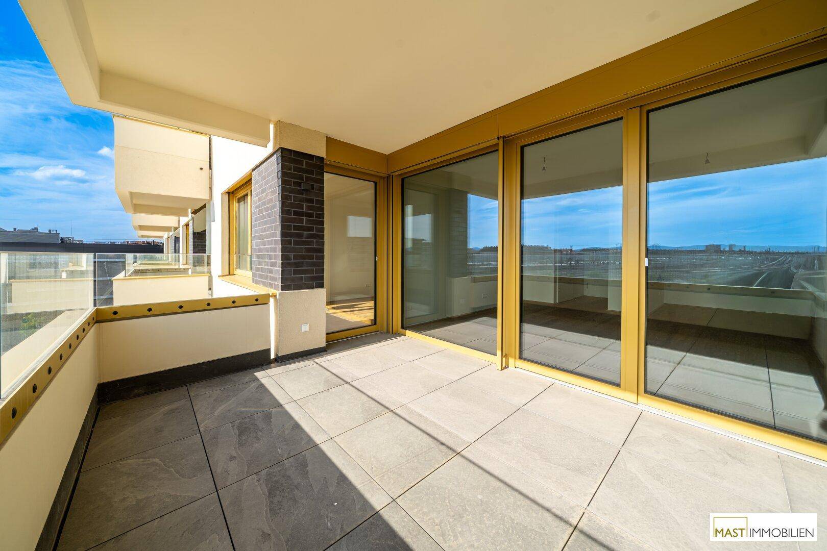 Heller Balkon mit modernen Fliesen und raumhohen Fenstern zum Innenbereich.