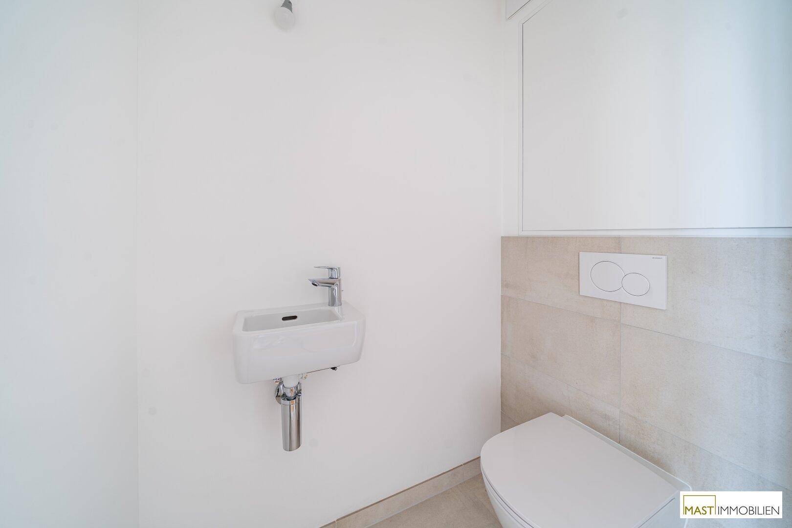 Separates Gäste-WC mit wandhängender Toilette und kleinem Handwaschbecken.