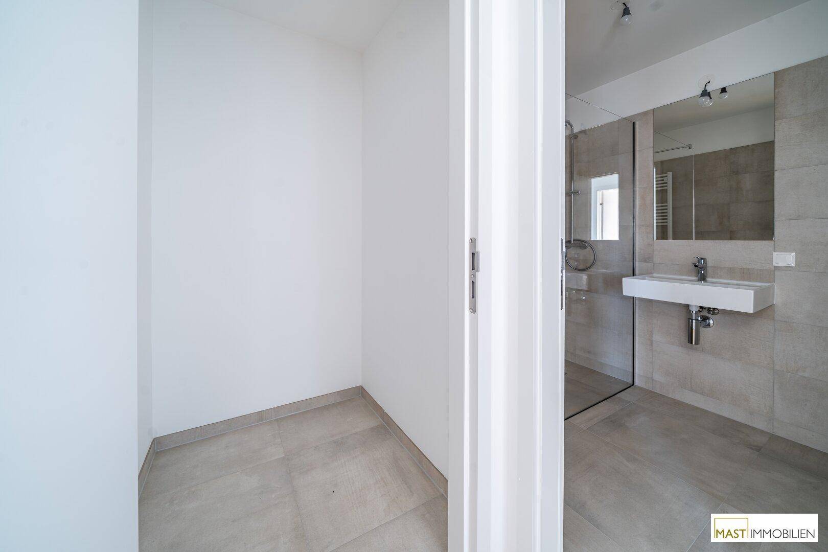 Modernes Badezimmer mit begehbarer Dusche, elegantem Waschbecken und hellen Fliesen.