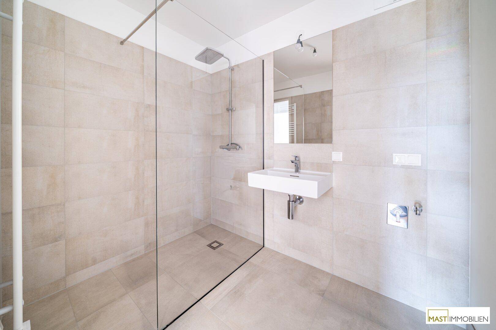 Geräumiges Badezimmer mit großer begehbarer Dusche, modernem Waschbecken und Wandspiegel.