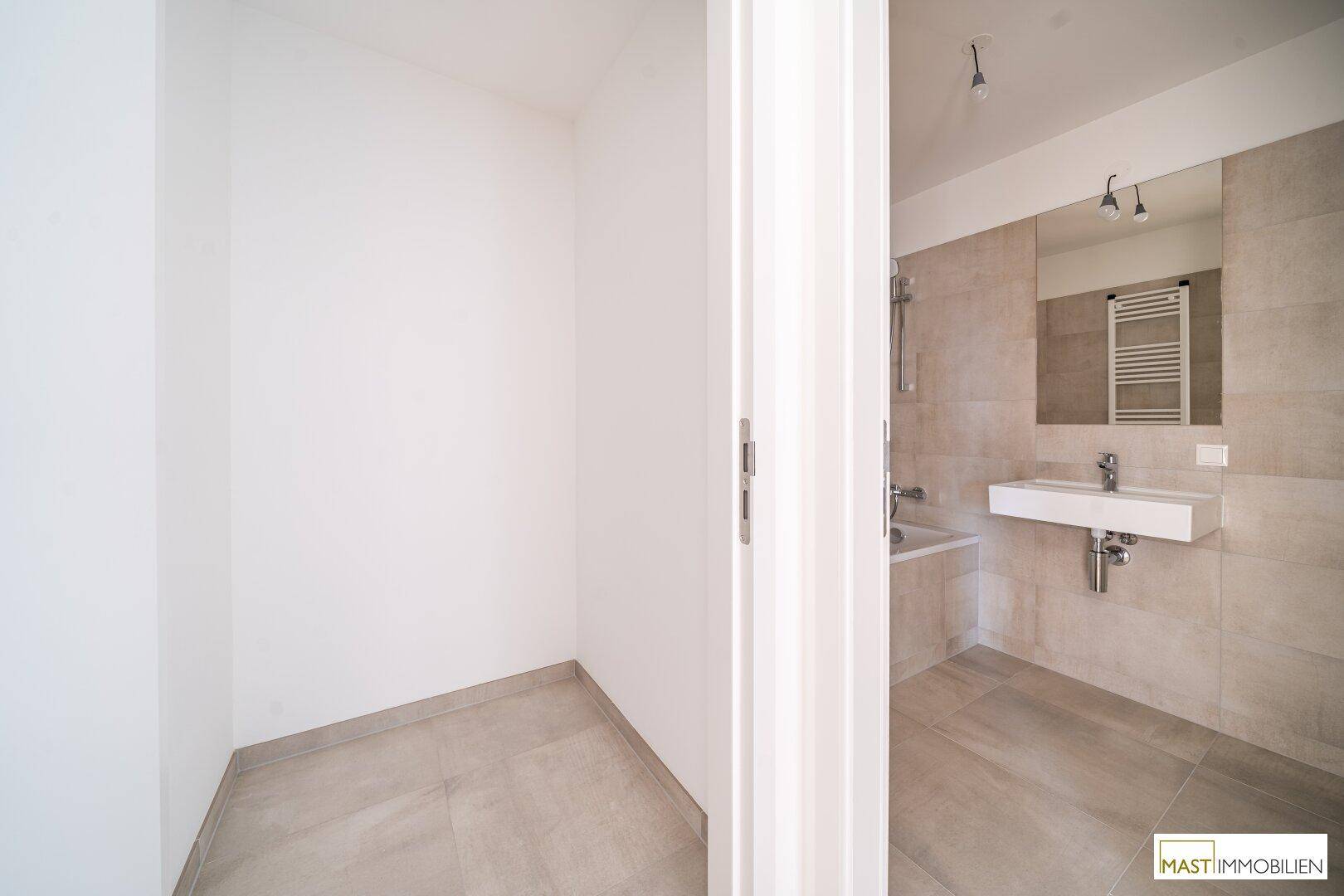 Heller Eingangsbereich mit Fliesenboden, der den Zugang zum modernen Badezimmer ermöglicht.