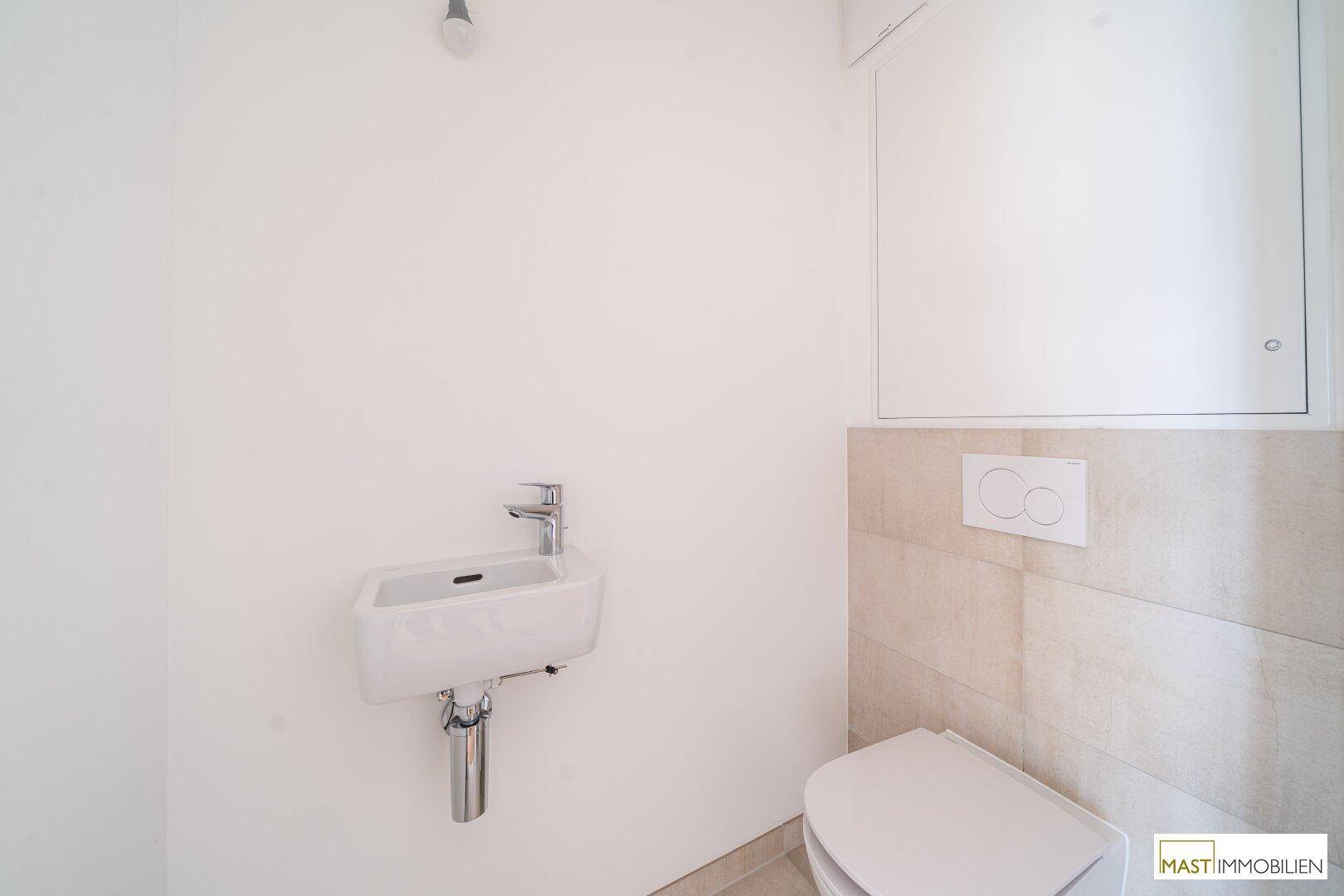Modernes Gäste-WC mit wandhängender Toilette und kleinem Waschbecken, in neutralen Farben gehalten.