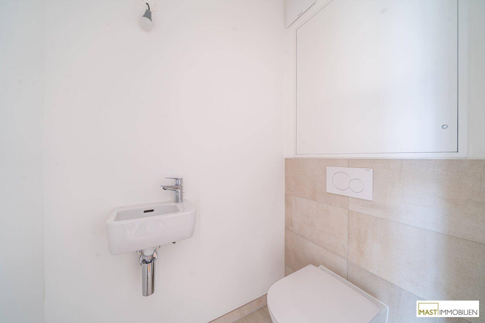 Modernes Gäste-WC mit wandhängender Toilette und kleinem Waschbecken.