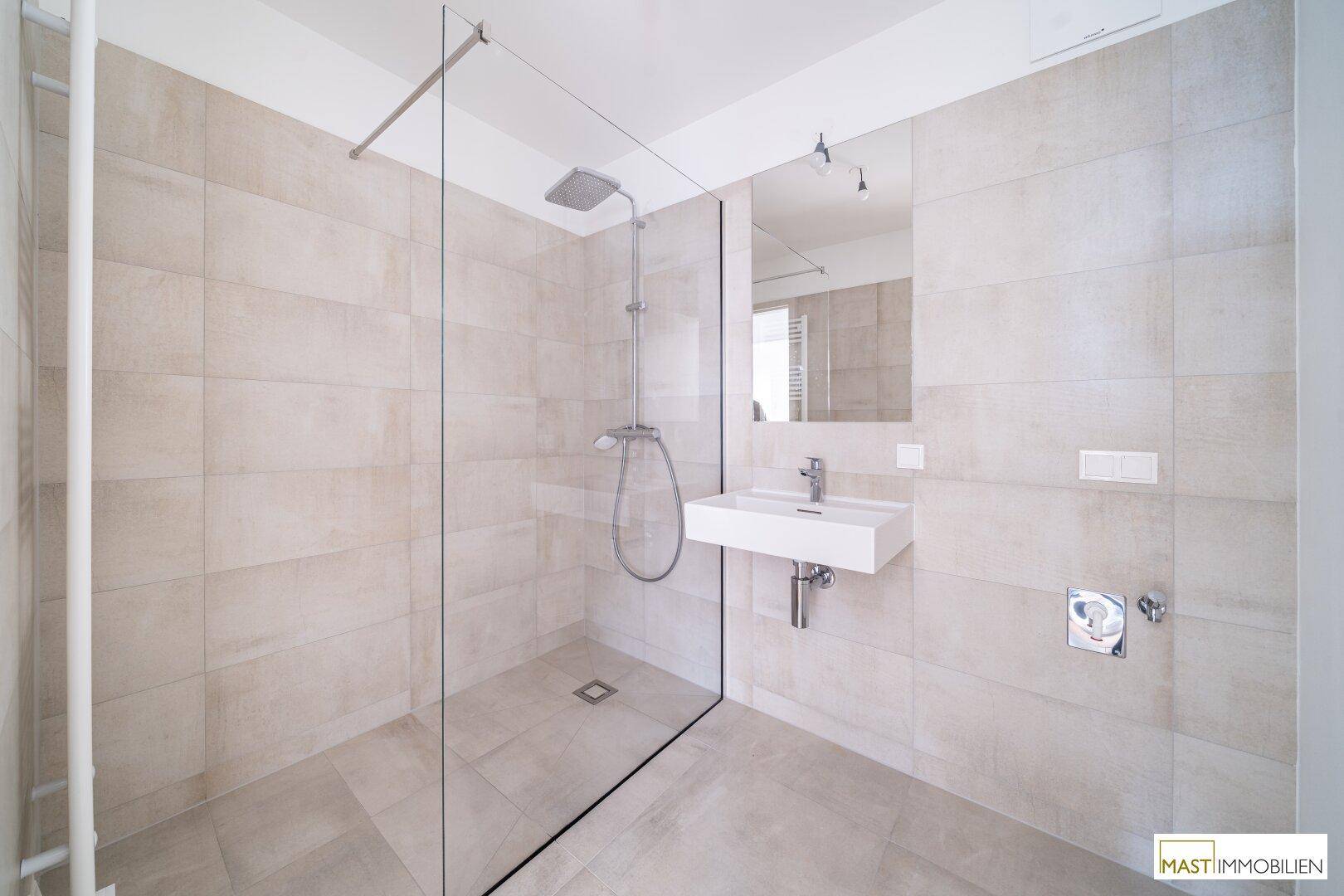 Modernes Badezimmer mit ebenerdiger Dusche und eleganten Fliesen, ausgestattet mit einem Einzelwaschbecken.