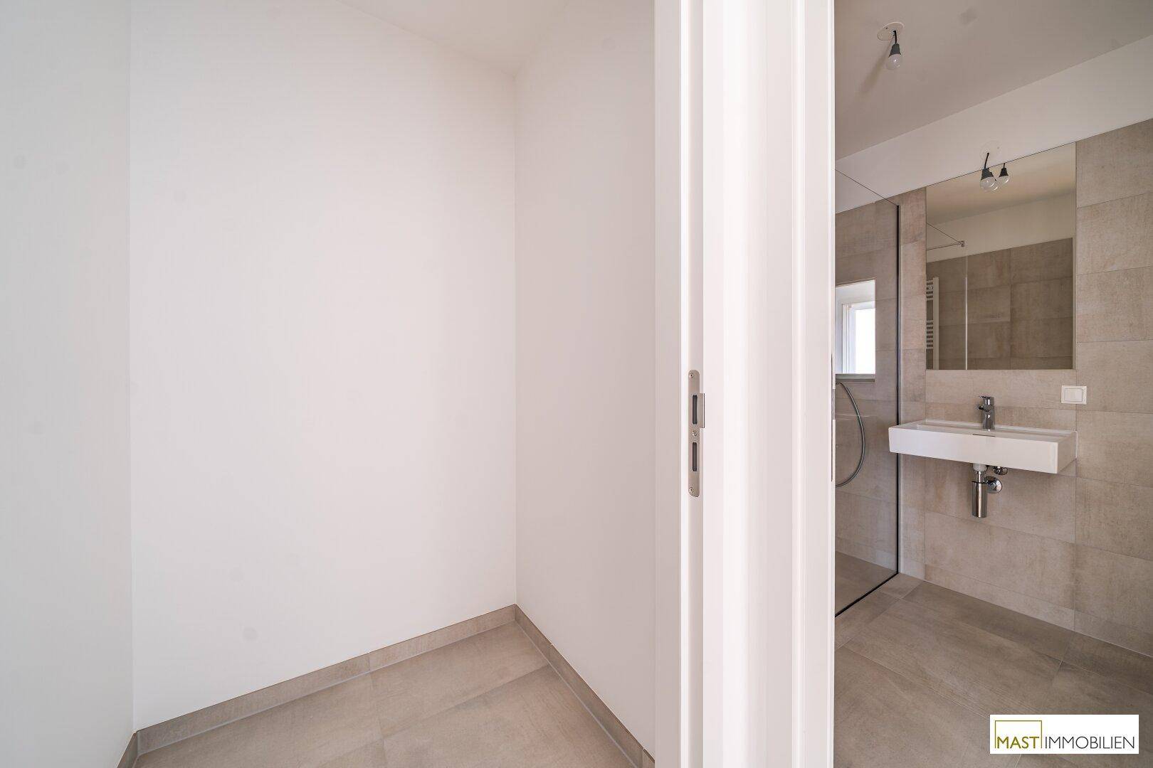 Kleiner, leerer Raum mit Fliesenboden, angrenzend an ein modernes Badezimmer.