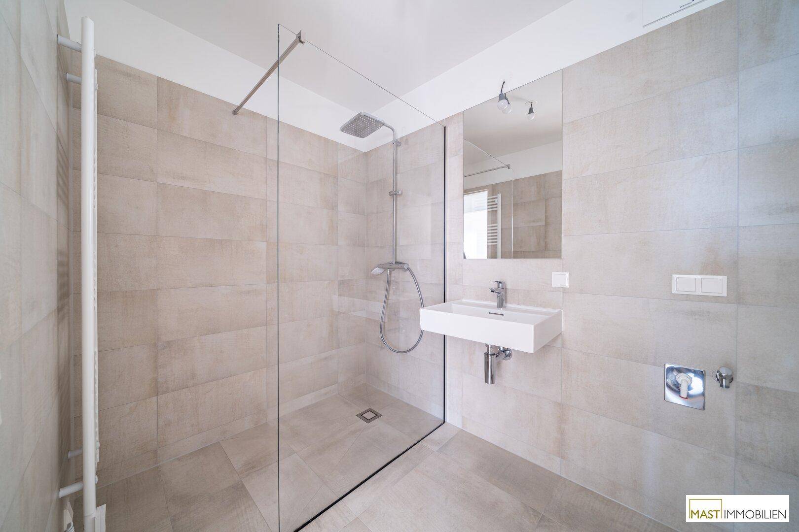 Modernes Badezimmer mit begehbarer Dusche, großformatigen Fliesen und beheiztem Handtuchhalter.