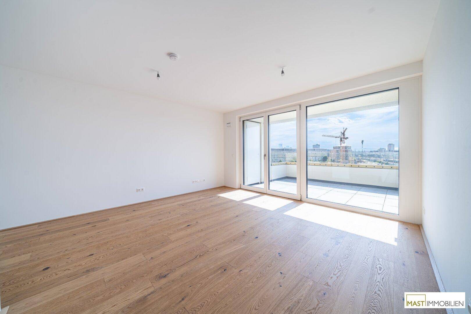 Lichtdurchfluteter Wohnbereich mit Holzboden und breiter Fensterfront zum Außenbereich.