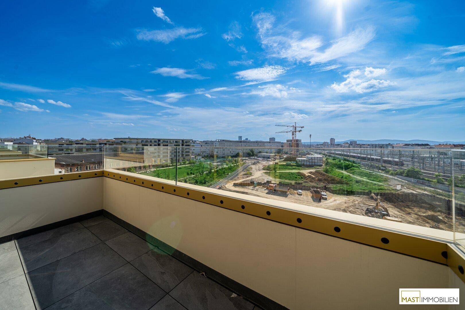 Sonniger Außenbereich mit Fliesenboden und weitem Blick über die Stadt und die umliegende Landschaft.