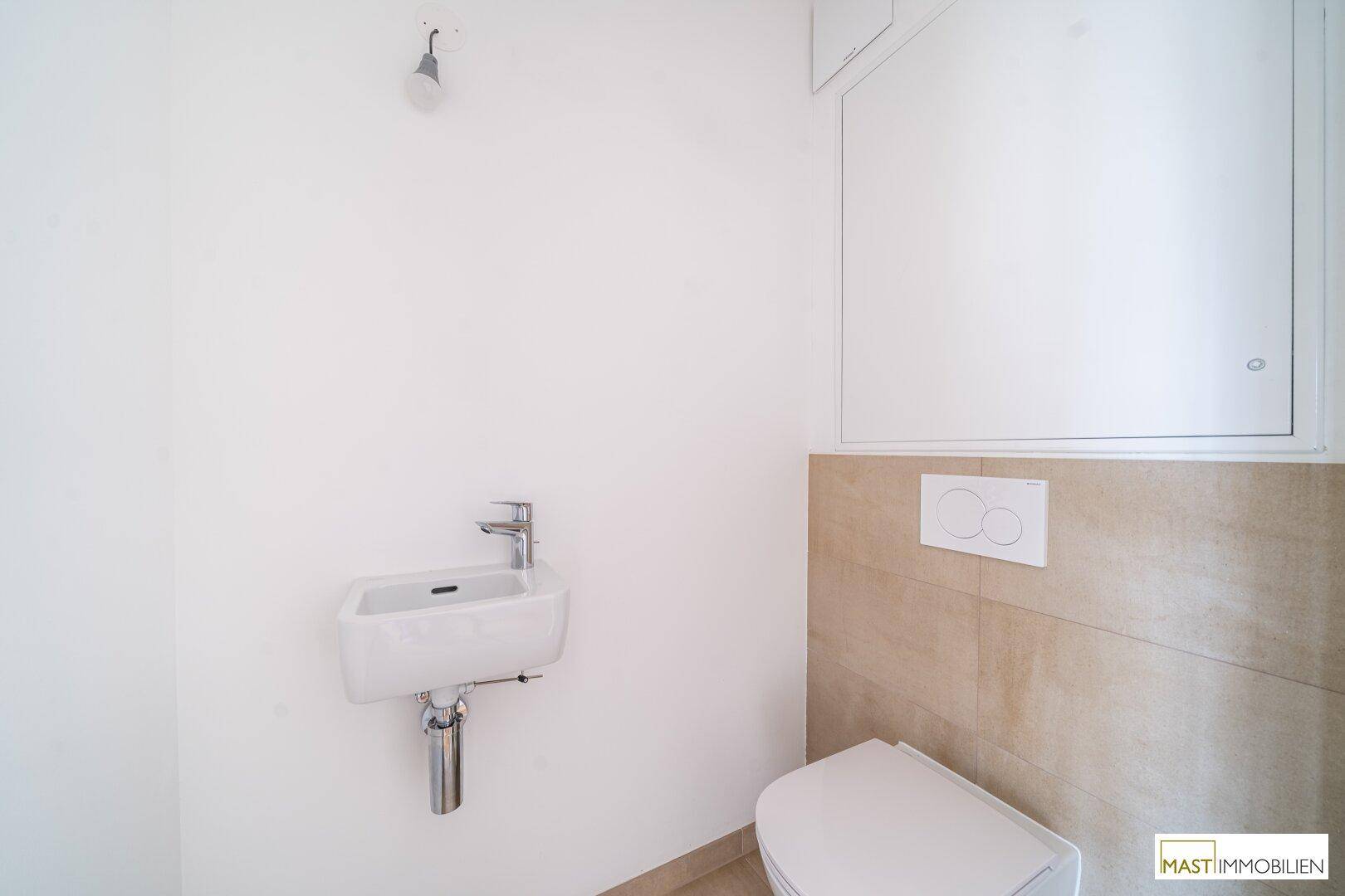 Funktionales Gäste-WC mit kleinem Waschbecken und Wand-WC, ausgestattet mit modernen Fliesen.
