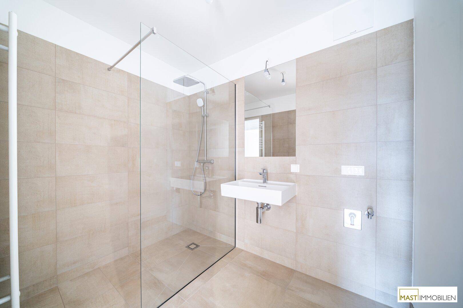 Modernes Badezimmer mit beigefarbenen Fliesen, einer begehbaren Dusche und einem eleganten Waschtisch.