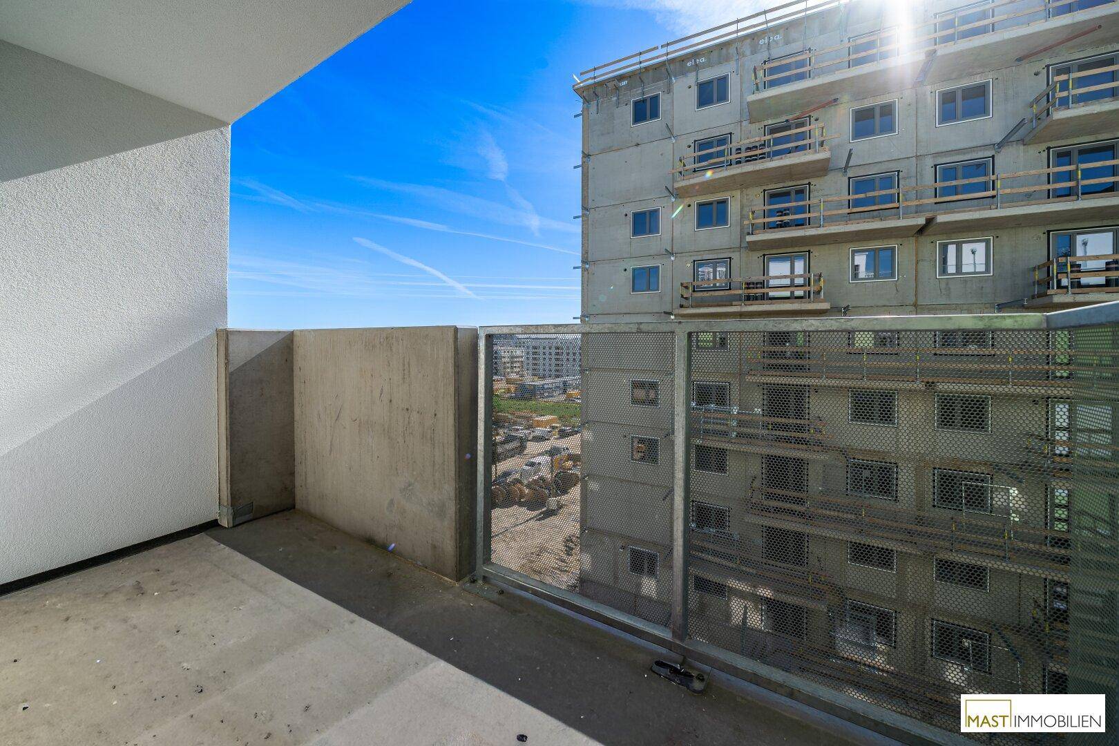 Unfertiger Balkon eines Neubaus mit Blick auf die Baustelle und umliegende Gebäude.