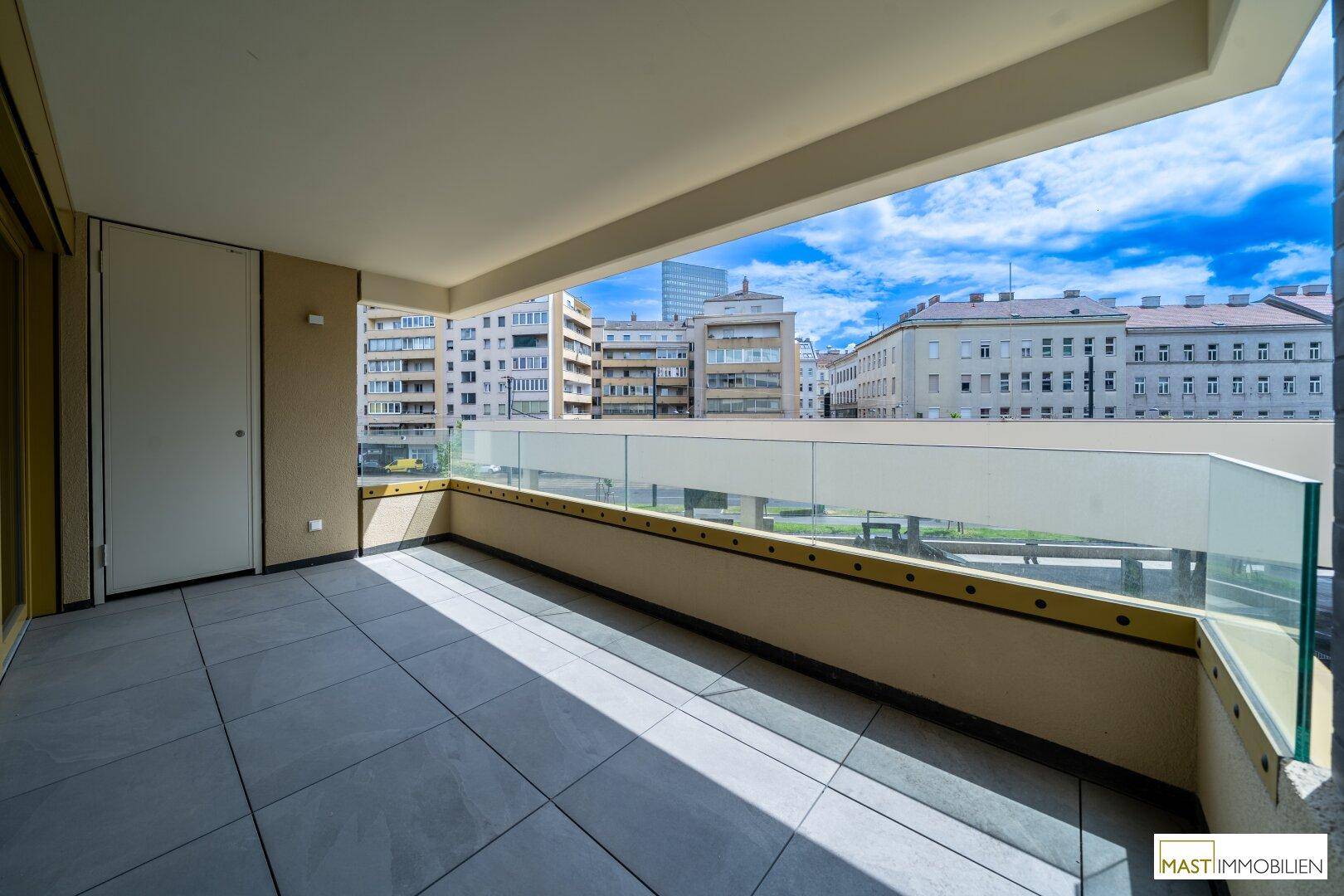 Großer Balkon mit weitem Stadtblick und Glasgeländer, ideal für entspannte Stunden im Freien.