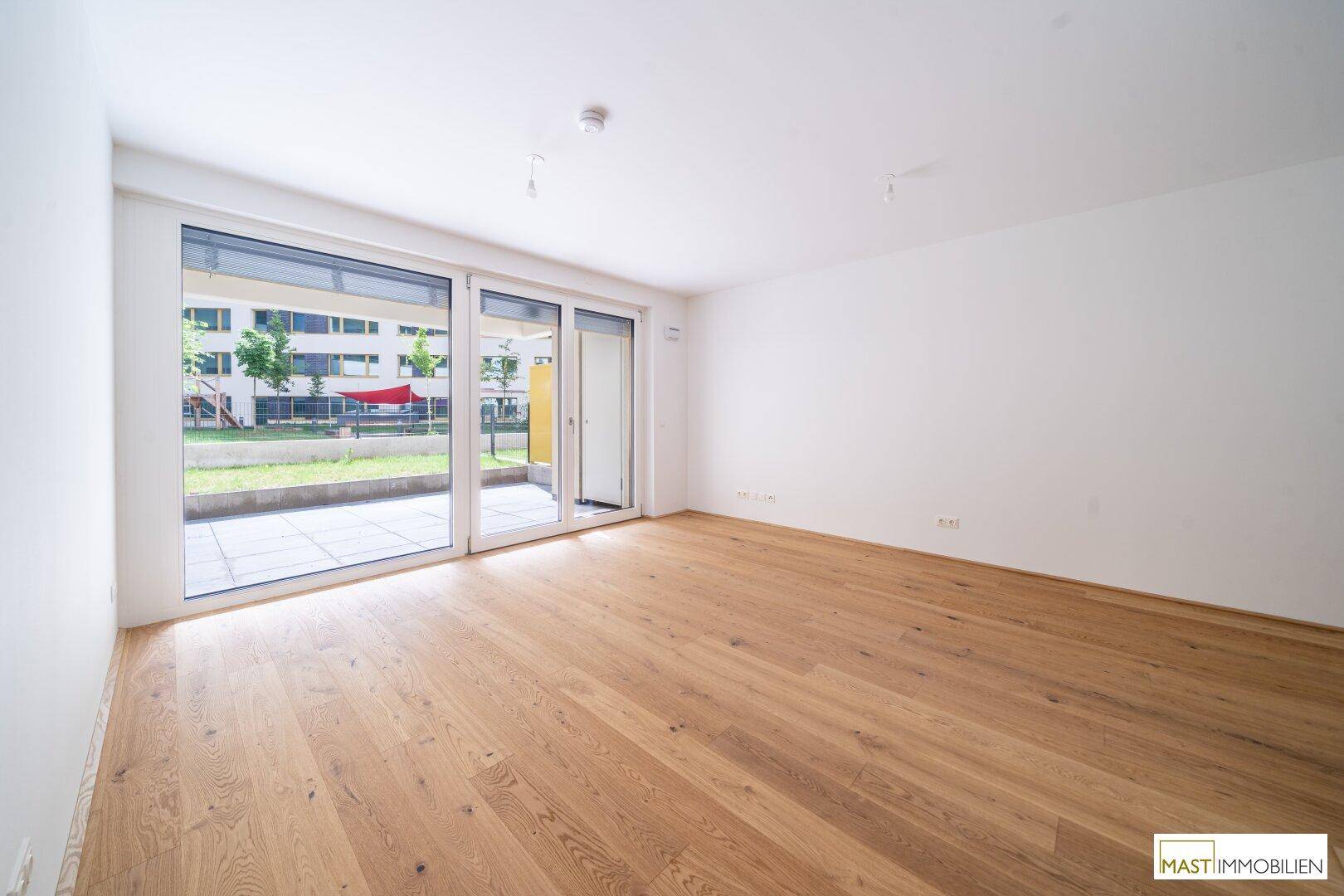 Heller Wohnraum mit Eichenparkettboden und großen Fenstern zum Gartenbereich.